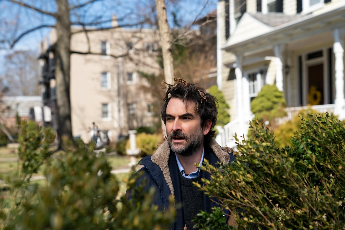 Jay Duplass stands in bushes with leaves in his hair as Bill Dobson in 'The Chair' Season 1
