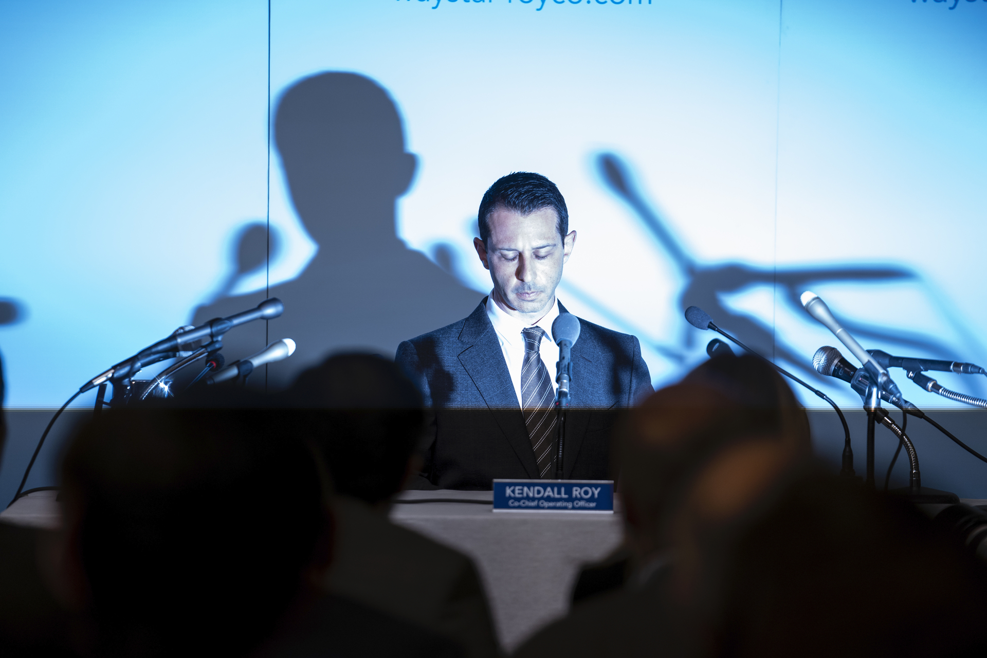 Jeremy Strong speaks at a press conference in front a number of microphones in 'Succession.'