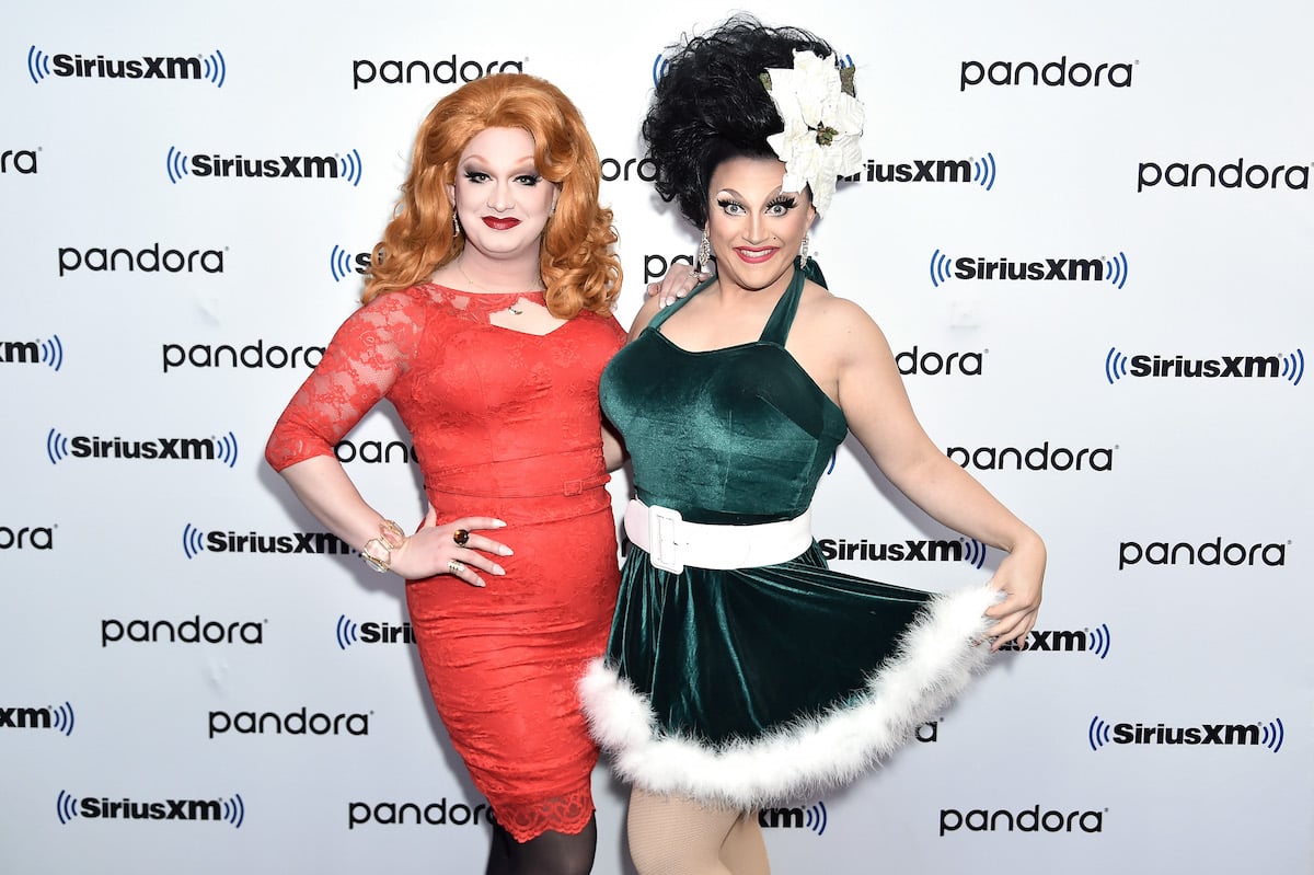 Jinkx Monsoon and BenDeLaCreme pose together in festive red and green attire at an event.