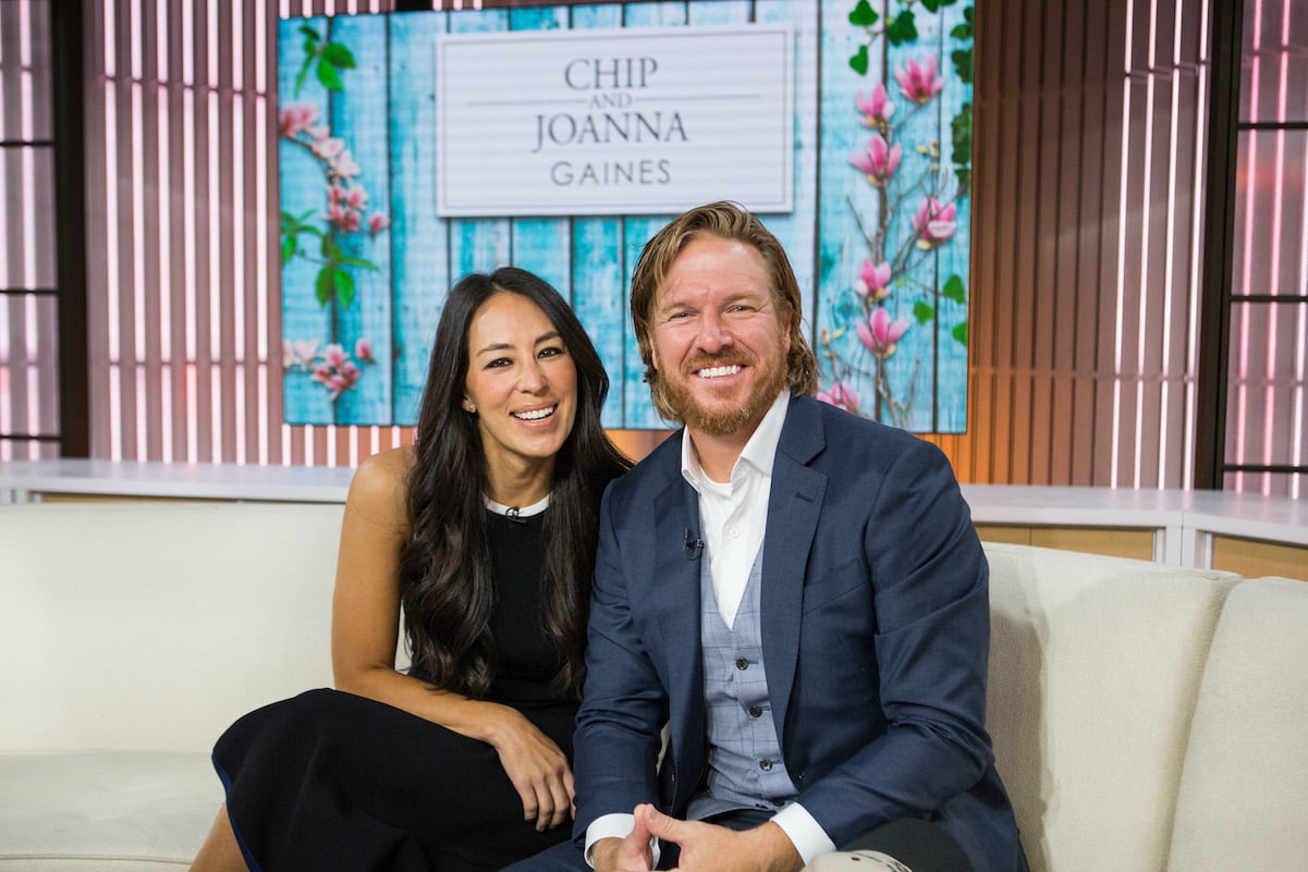 Chip and Joanna Gaines smiling while sitting on the couch