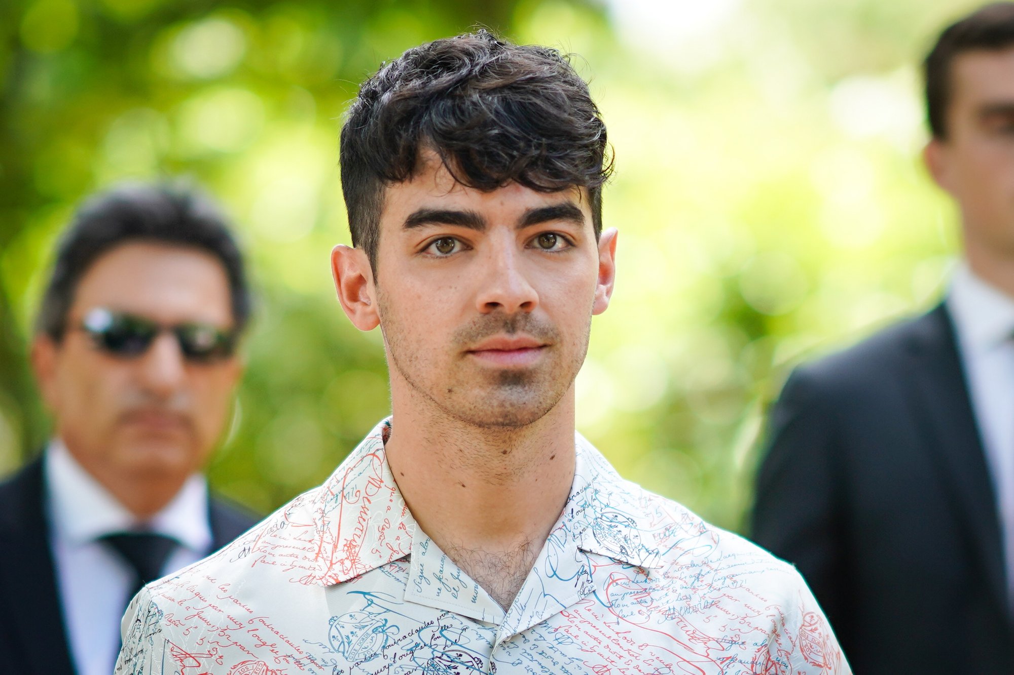 Joe Jonas smiling slightly in front of a blurred background