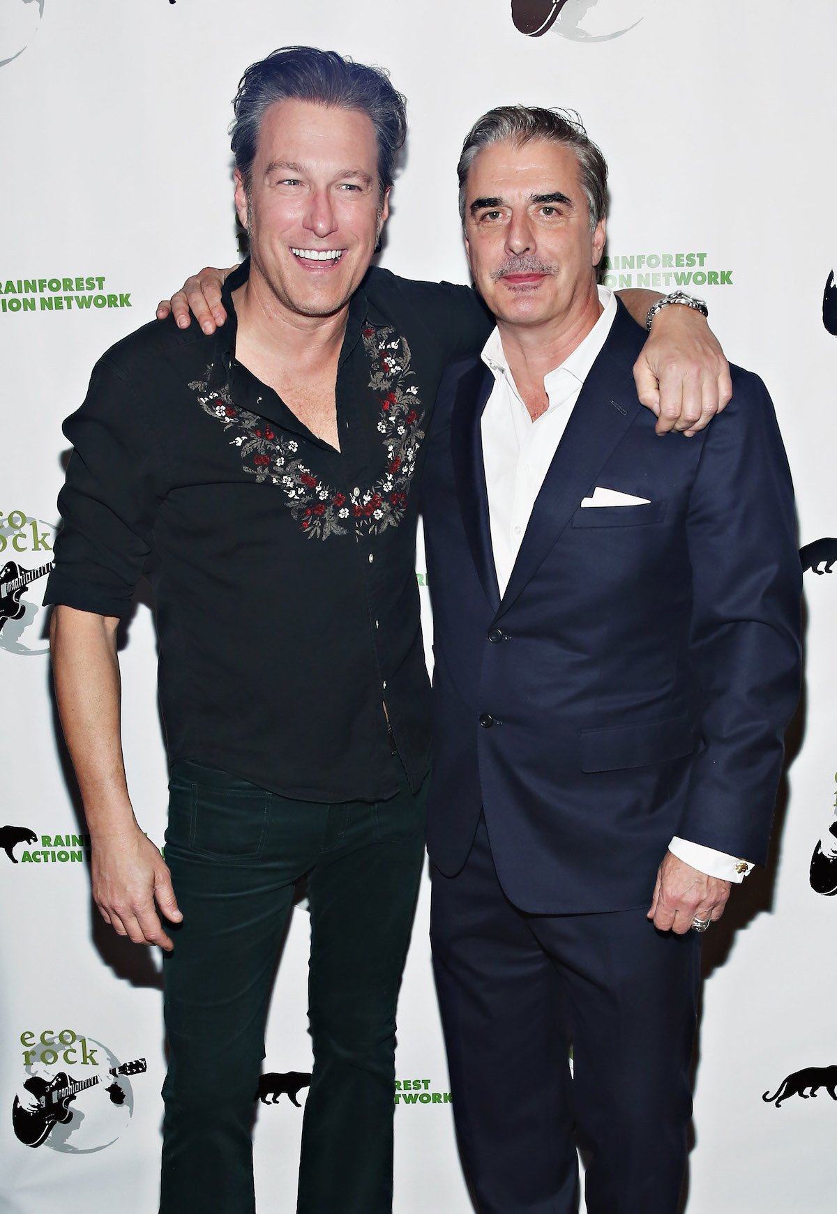 John Corbett and Chris Noth pose with their arms around each other at an event.