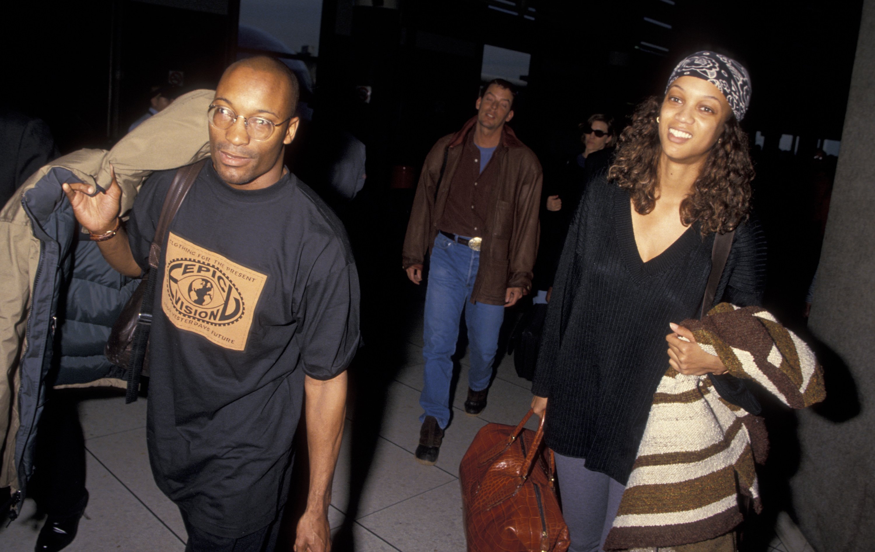 John Singleton and Tyra Banks traveling in casual clothes and walking in the 1990s.