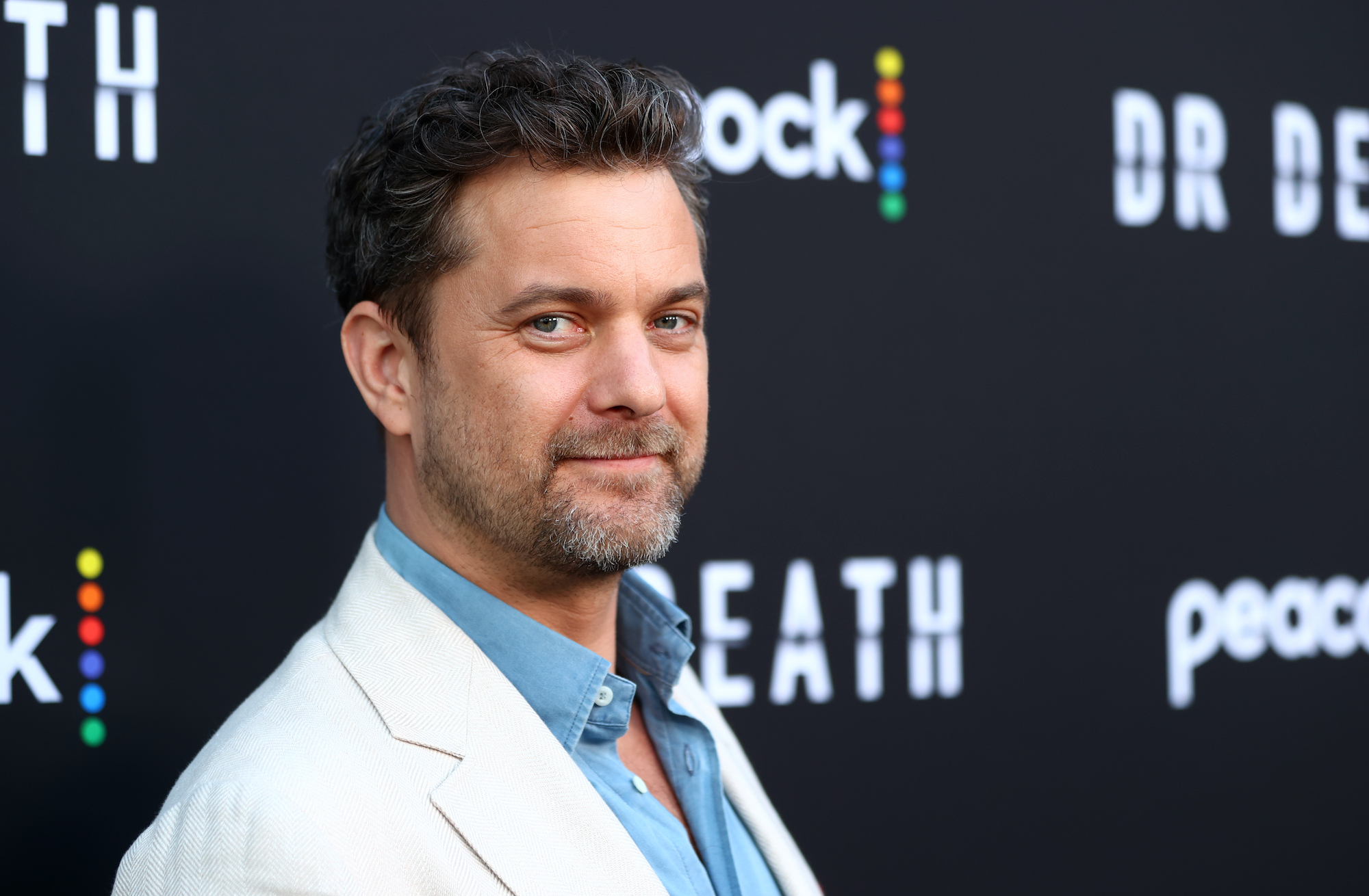 Joshua Jackson smiling in front of a black background