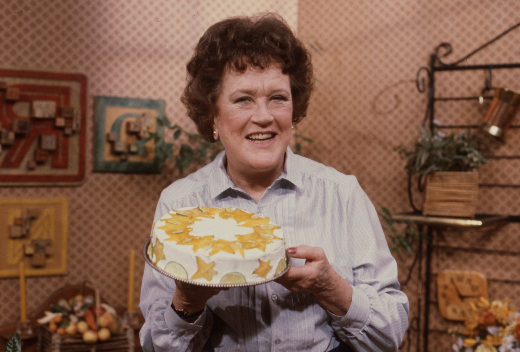 Julia stands in her kitchen holding up a cake during a taping of her show,'The French Cook'