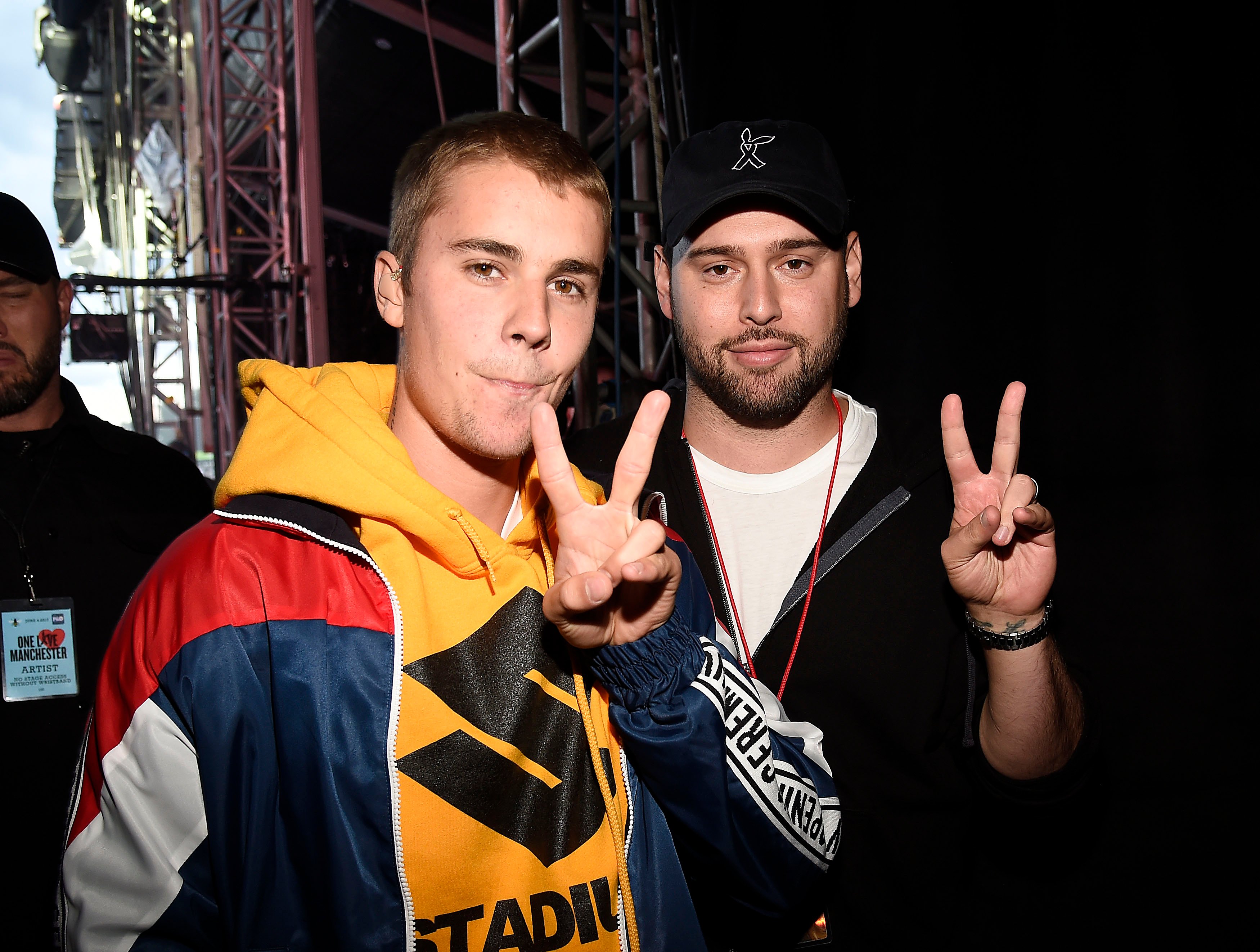 Justin Bieber and Scooter Braun doing a peace sign backstage at a concert.