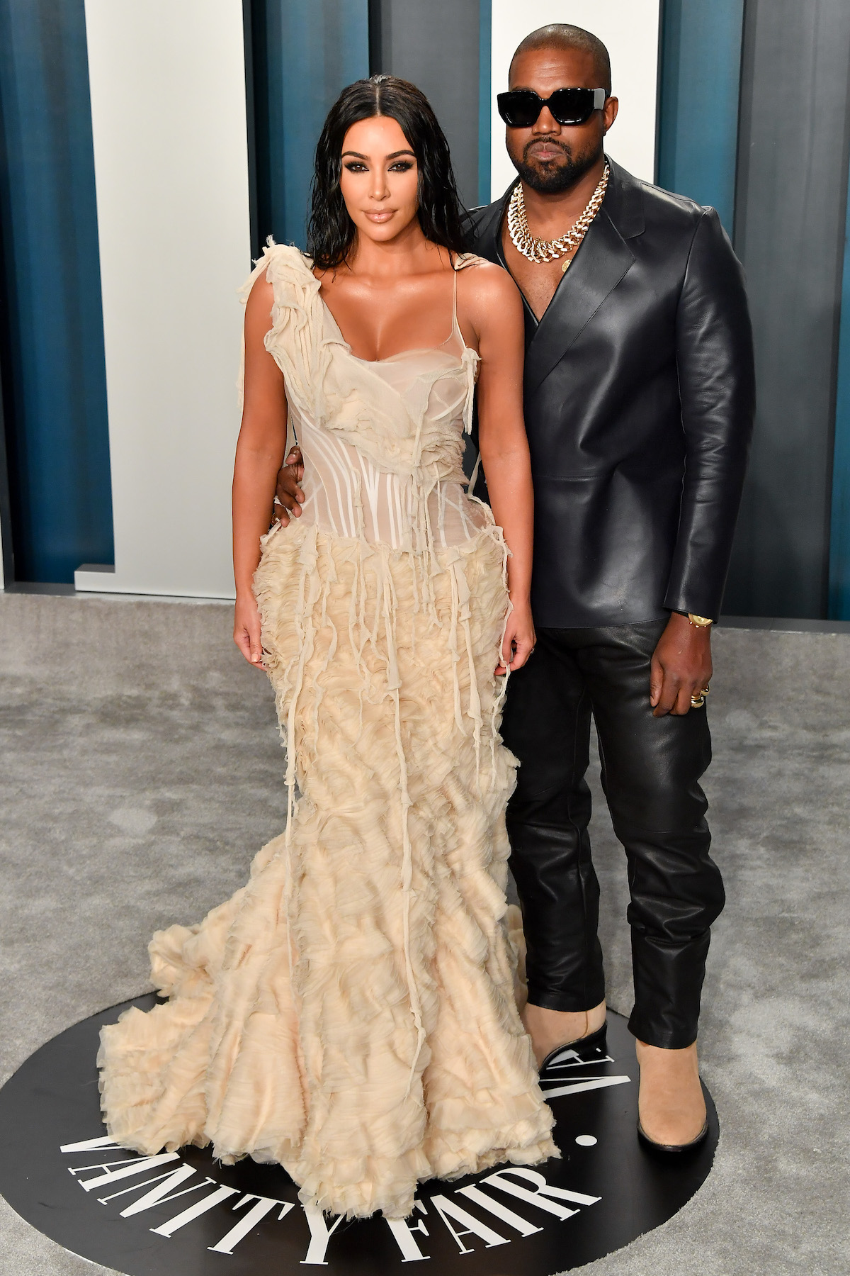 Kim Kardashian West poses in a long cream gown with her husband Kanye West at an event.