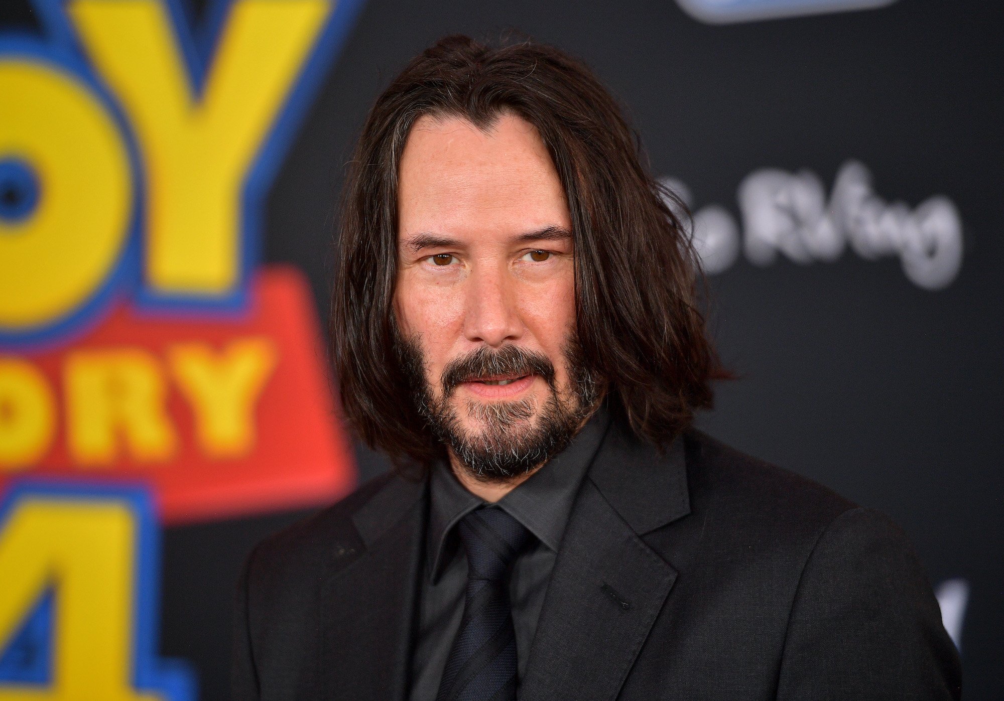 Keanu Reeves smiling in front of a black background