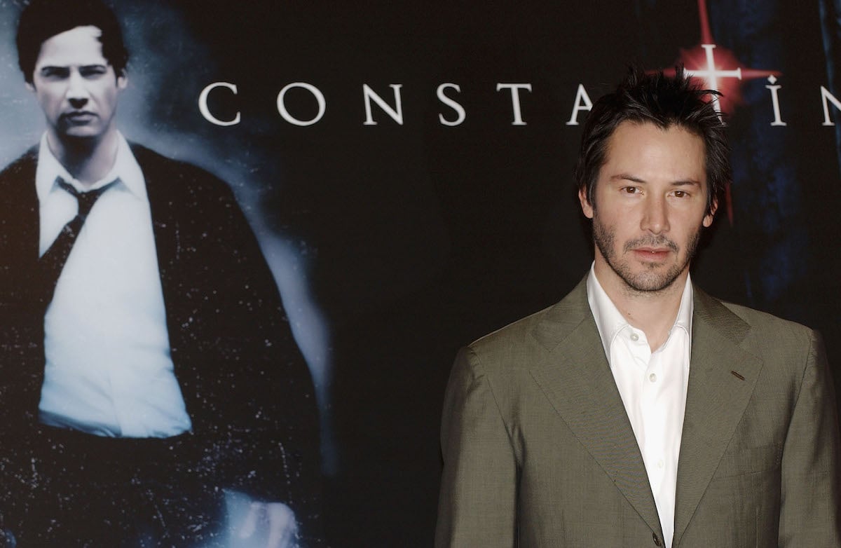 Keanu Reeves standing in front of 'Constantine' poster
