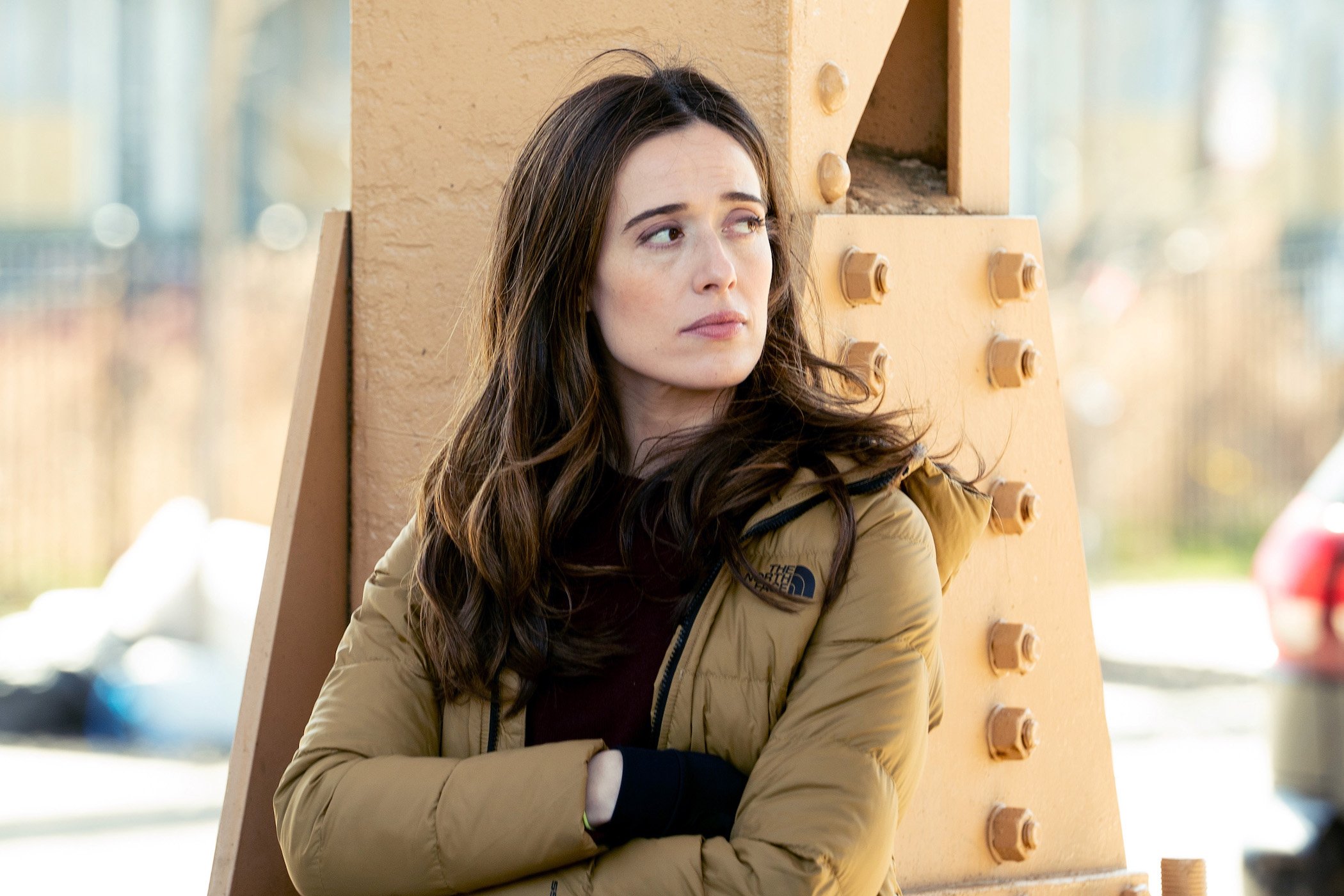 Marina Squerciati as Kim Burgess, a star in 'Chicago P.D.' Season 9, with her arms crossed leaning against a structure