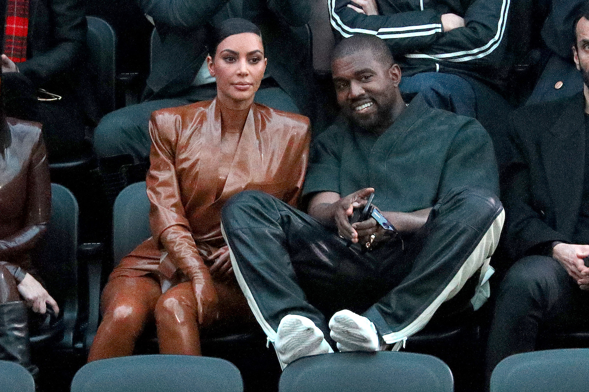 Kim Kardashian West and Kanye West sit together at a fashion show.