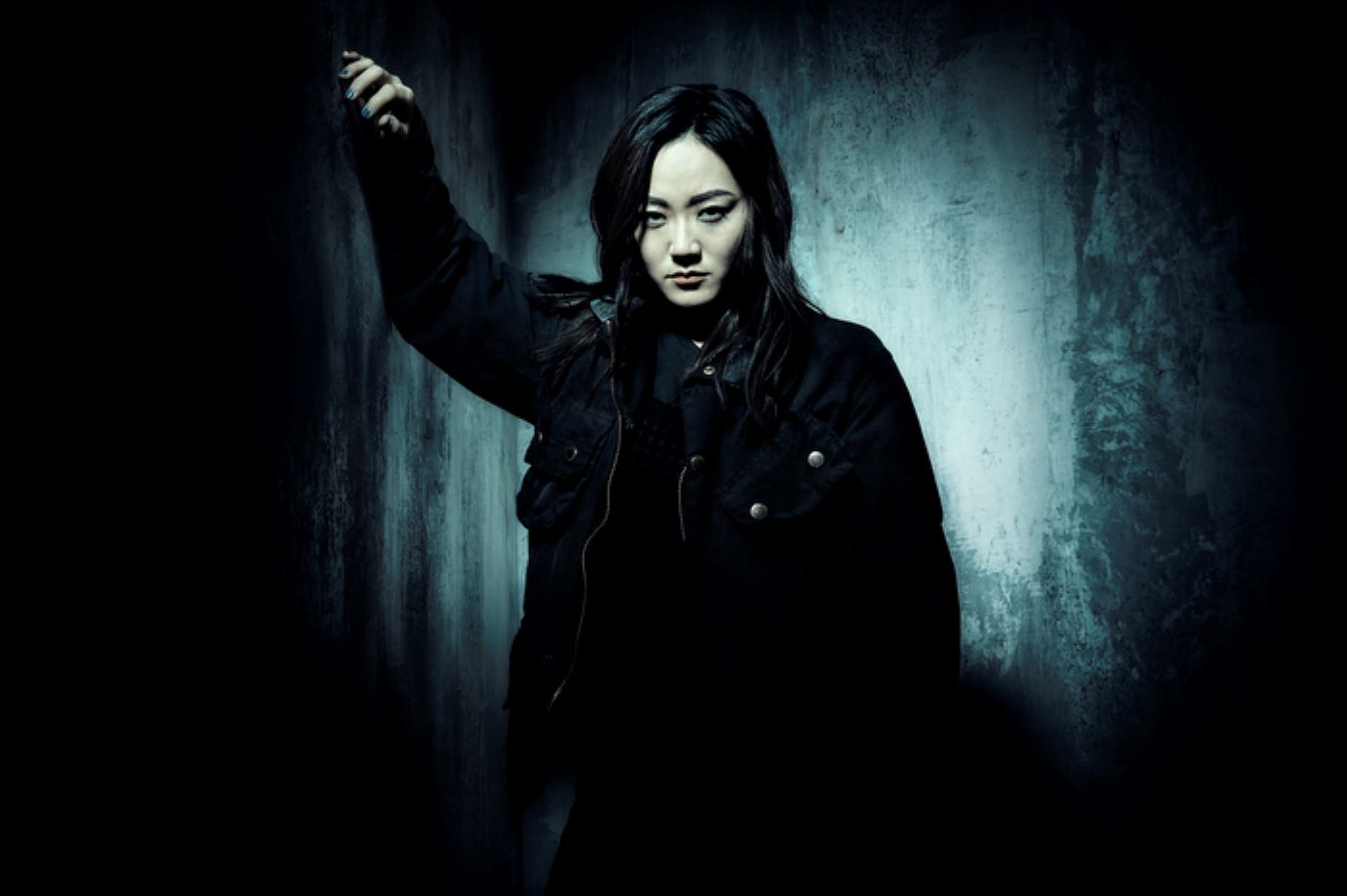Kimiko from 'The Boys' is wearing a black jacket and pants against a drastic vignette with a grey center.