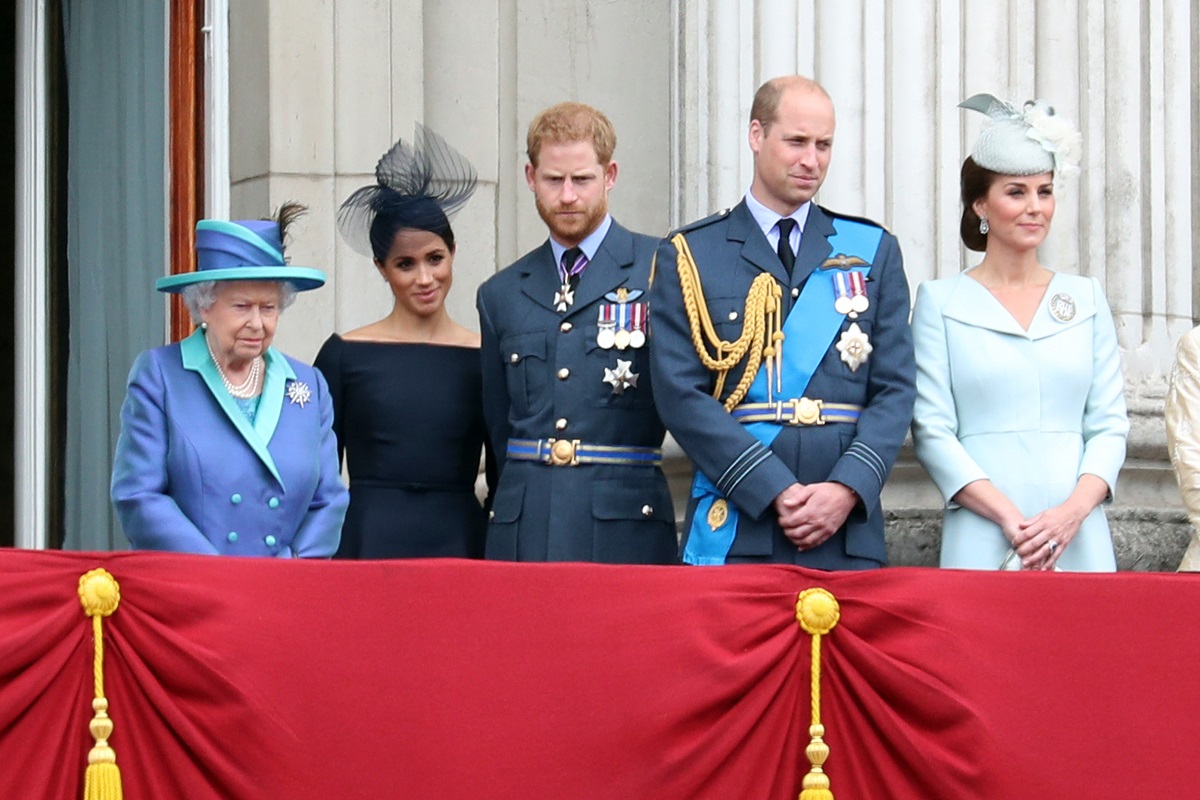 (L-R) Queen Elizabeth II, Meghan Markle, Prince Harry, Prince William, and Kate Middleton standing on the balcony of Buckingham Palace to watch a flypast