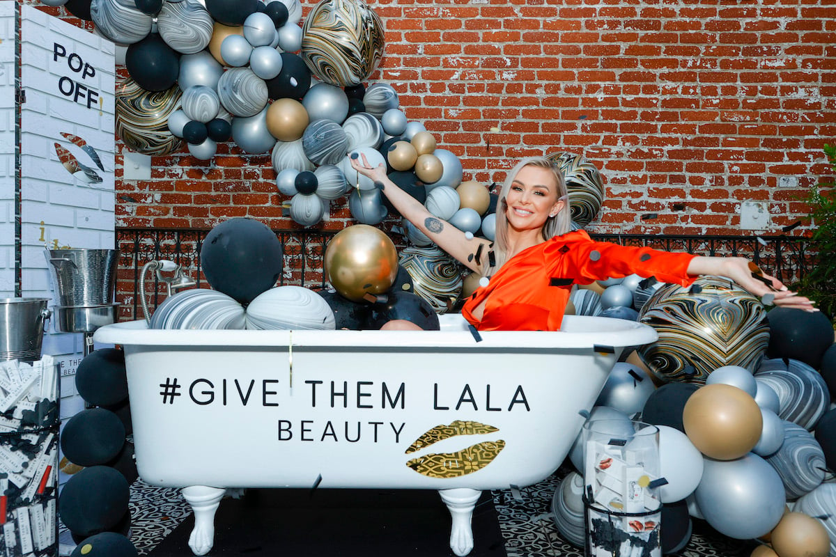 Lala Kent poses in a bathtub wearing a red dress surrounded by balloons.