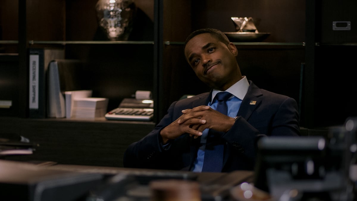 Larenz Tate sits behind a desk and claps his hands while wearing a suit as Rashad Tate in 'Power
