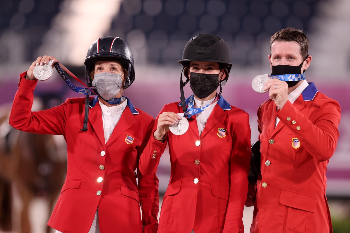 Laura Kraut, Jessica Springsteen and McLain Ward hold up their silver medals wearing equestrian gear and face masks