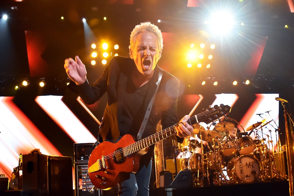 Lindsey Buckingham intensely playing guitar with a concentrated face on stage.