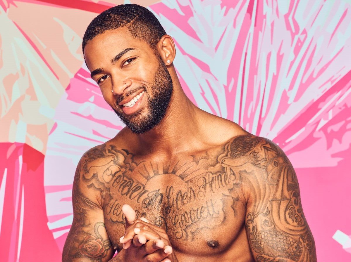 Charlie Lynch of 'Love Island' is shirtless and smiling rubbing his hands together.
