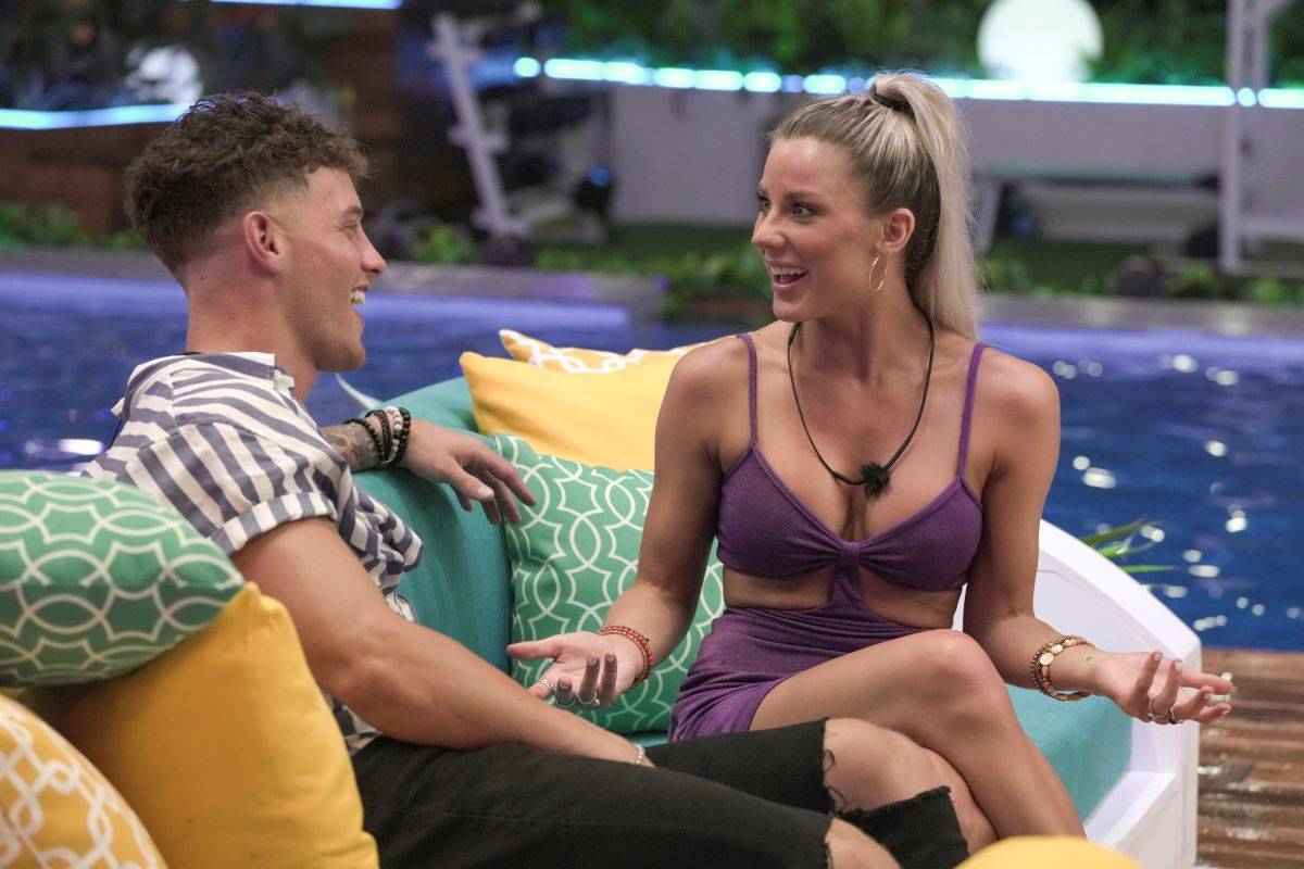 Josh Goldstein and Shannon St. Clair of 'Love Island' sit down talking on a couch laughing..
