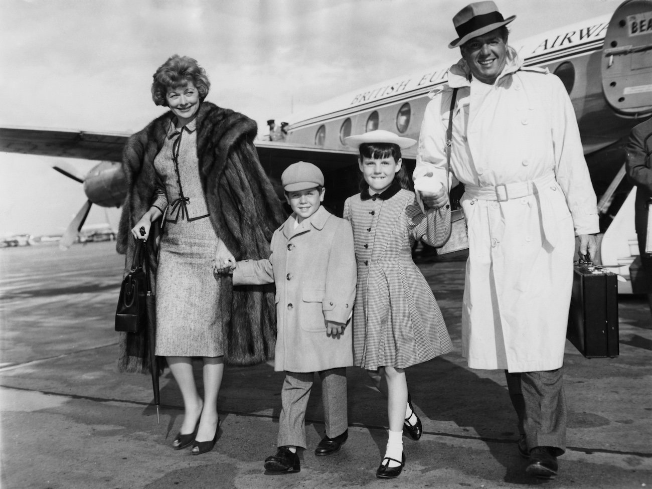 Lucille Ball and her husband, Desi Arnaz, hold hands with their children as they arrive at the airport in 1959