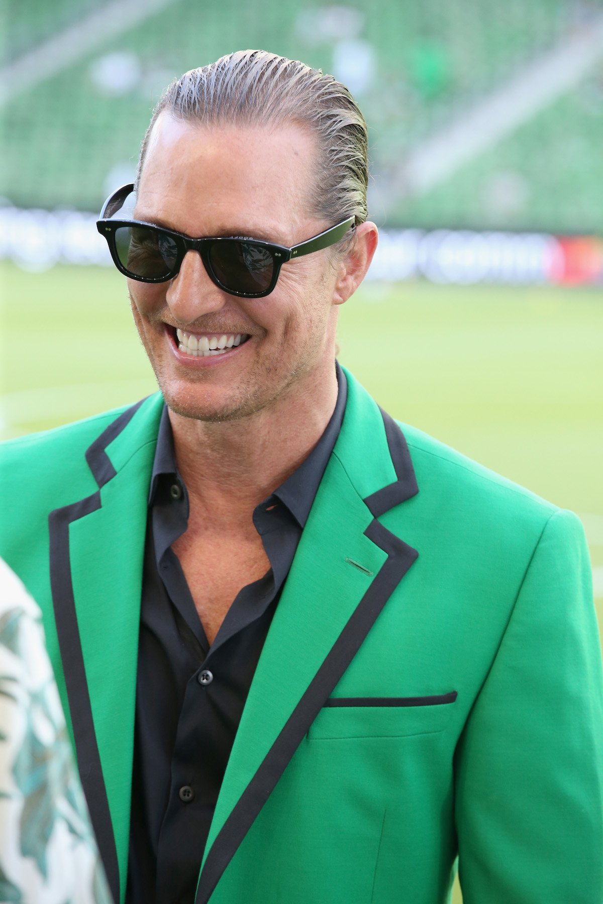 Matthew McConaughey wearing a green blazer and sunglasses smiling