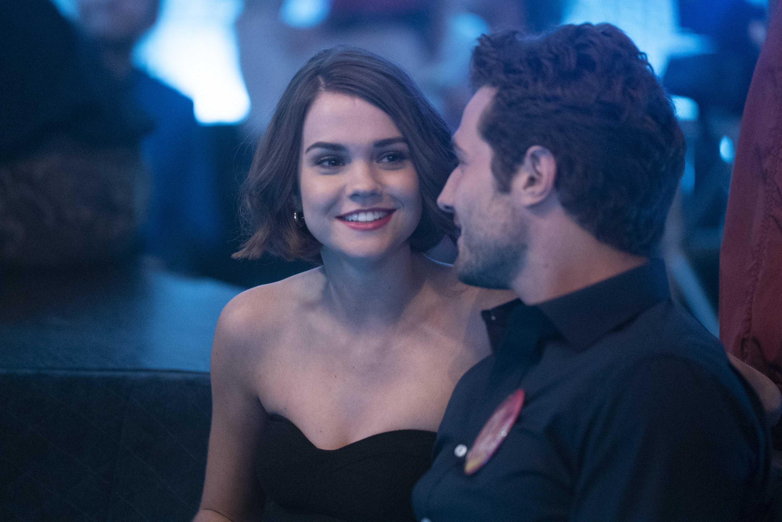 Maia Mitchell smiles while wearing a black dress on 'Good Trouble.'