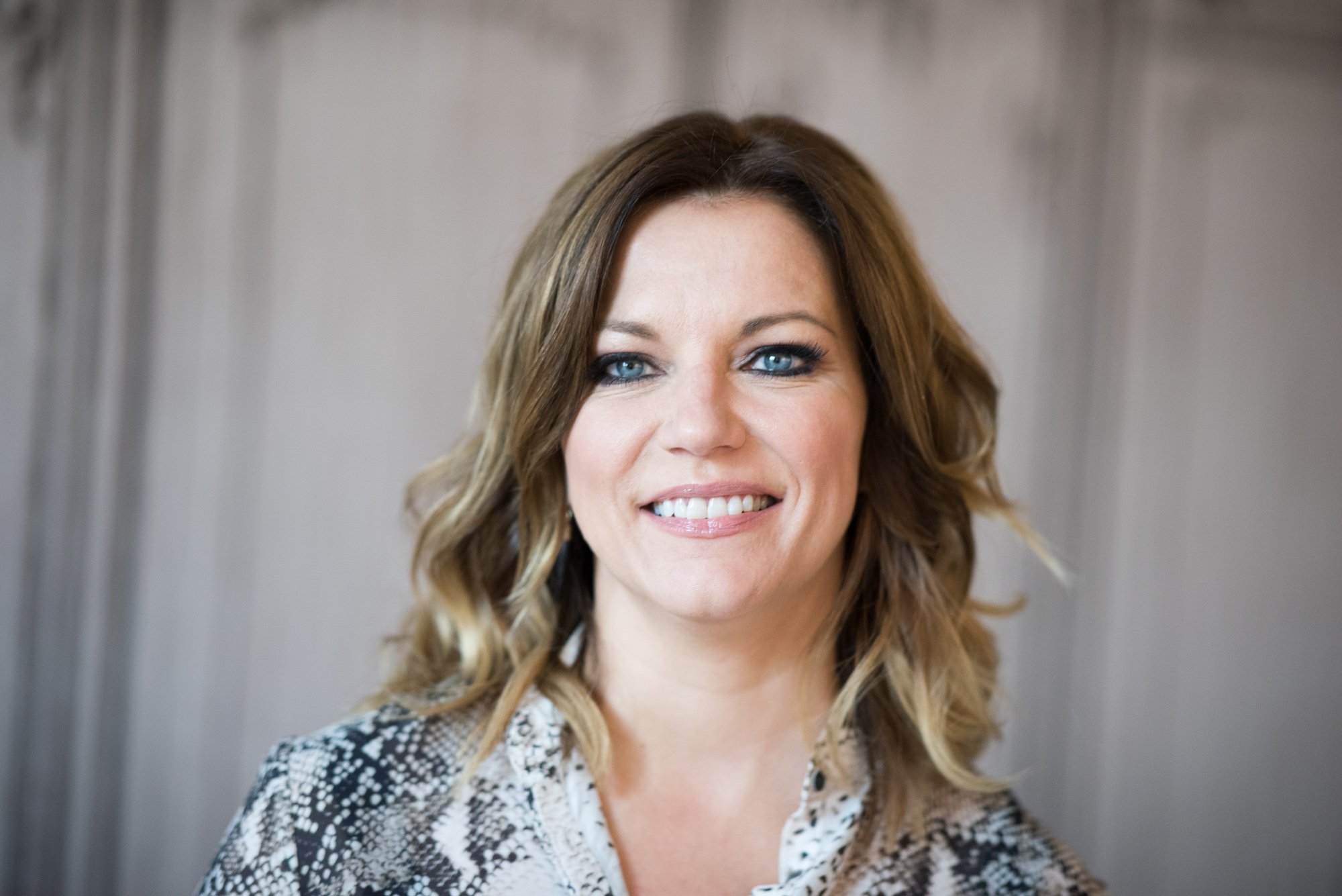 Martina McBride smiling in front of a blurred background