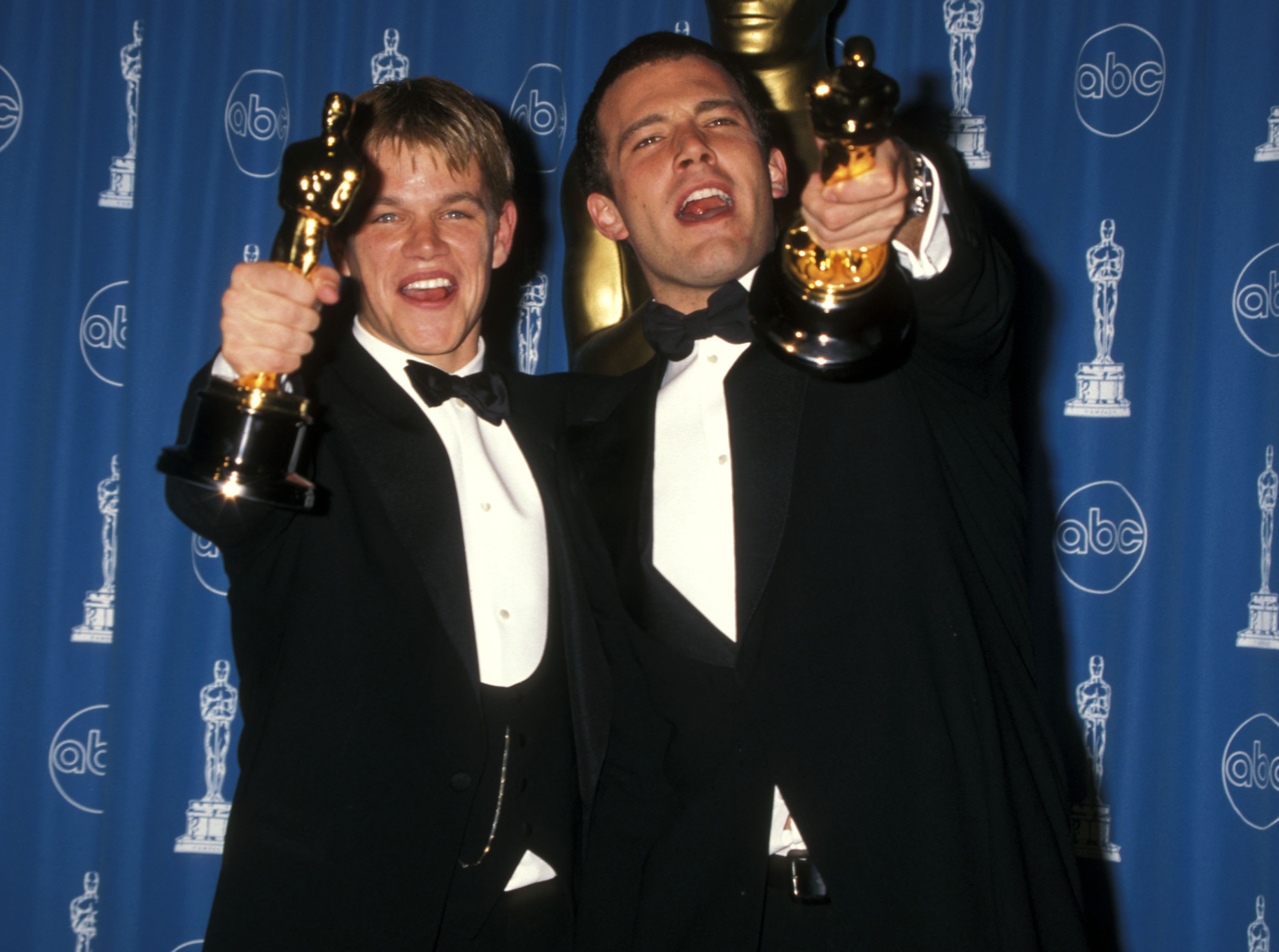 Matt Damon and Ben Affleck smiling and holding their Oscars for 'Good Will Hunting'