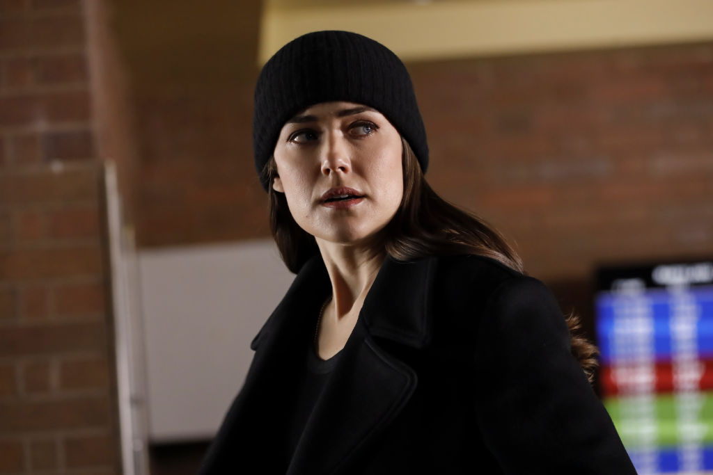 Megan Boone as Liz Keen. She's dressed in all black with a black cap as she looks over her shoulder.