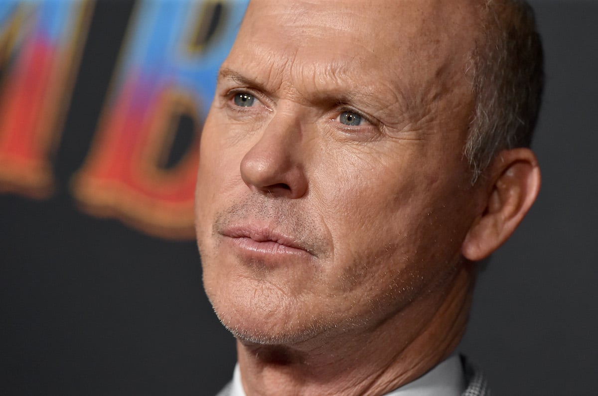 Michael Keaton poses on the red carpet wearing a gray suit