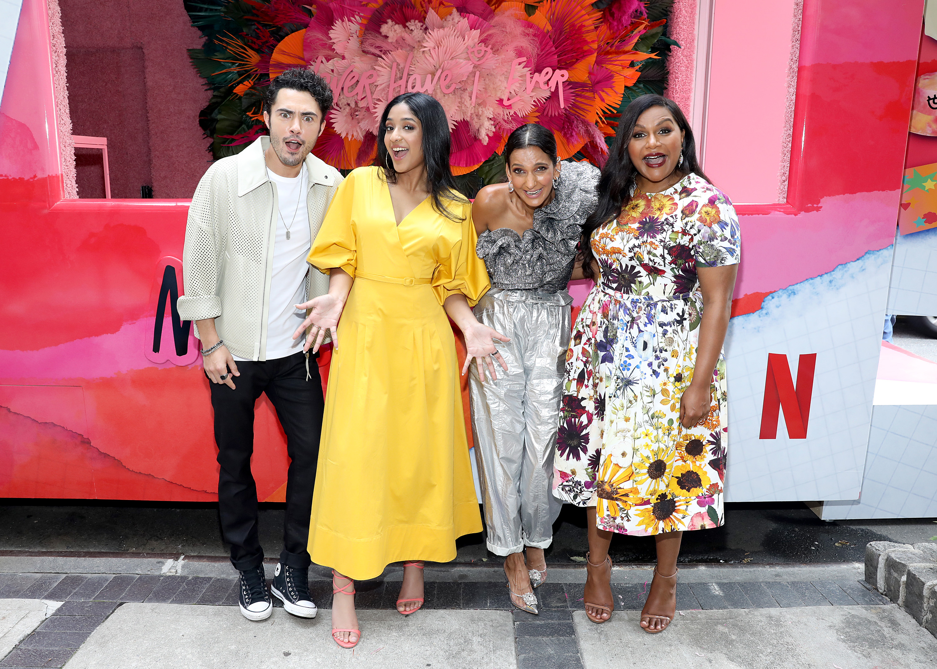 Darren Barnet, Maitreyi Ramakrishnan, Poorna Jagannathan, and Mindy Kaling 'Never Have I Ever' standing next to each other in front of Netflix truck