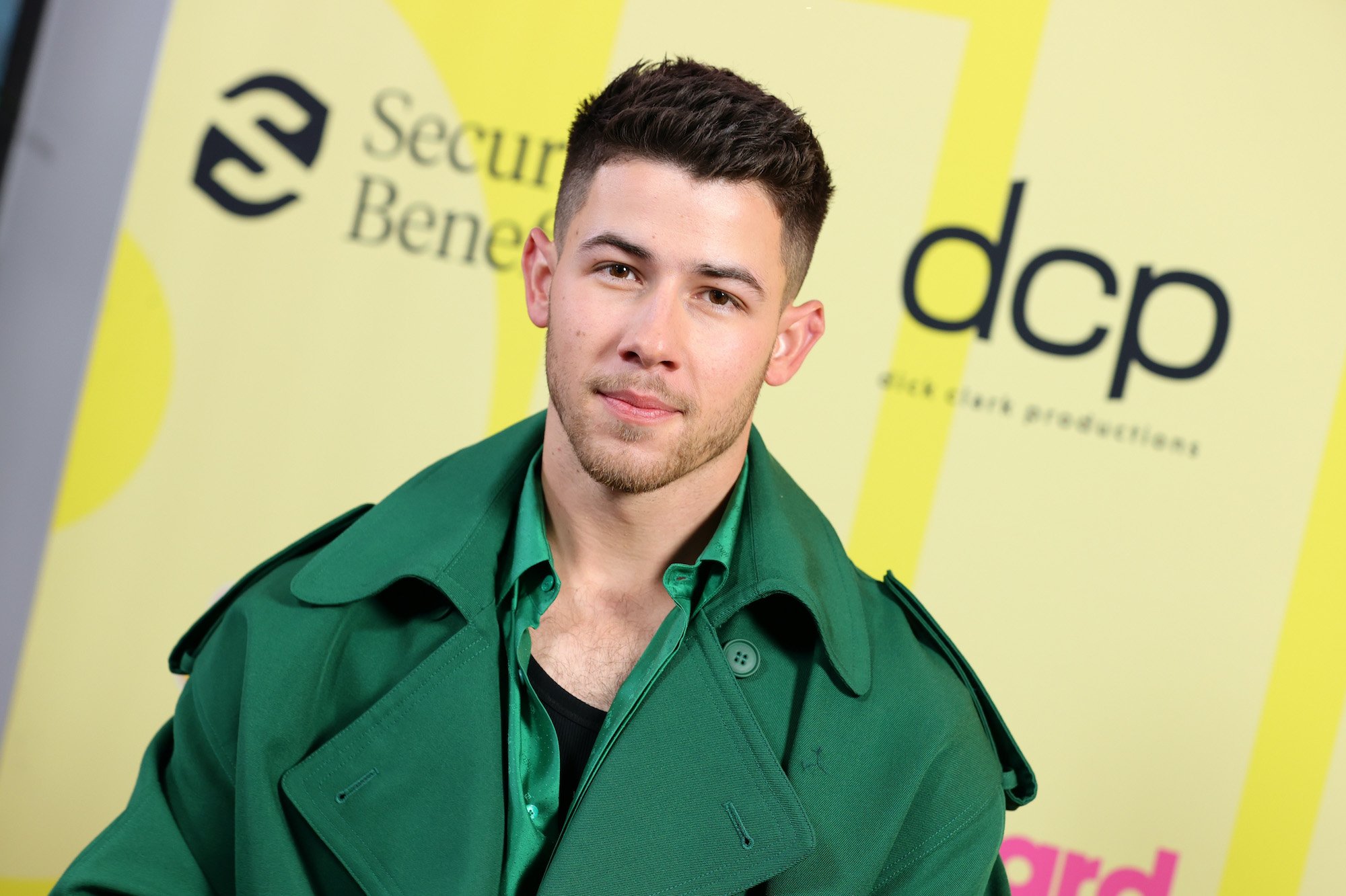 Nick Jonas smiling in front of a yellow background