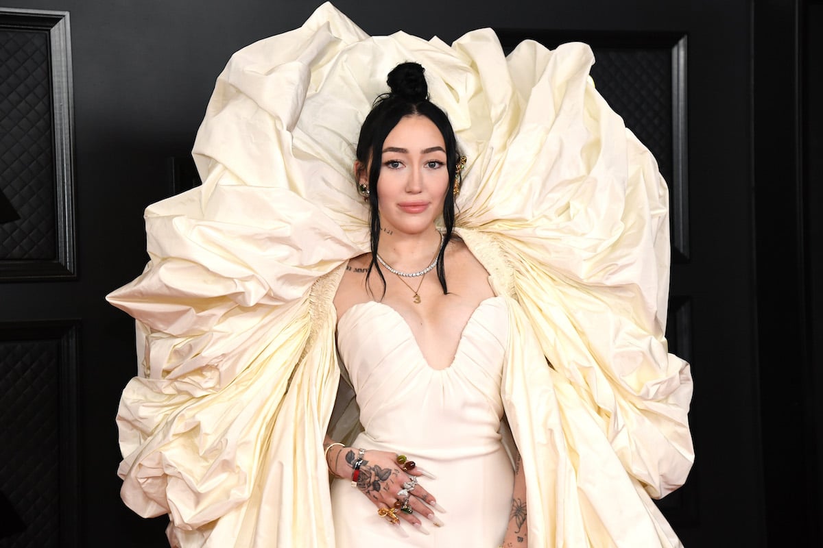 Noah Cyrus in an elaborate white gown poses for the camera.