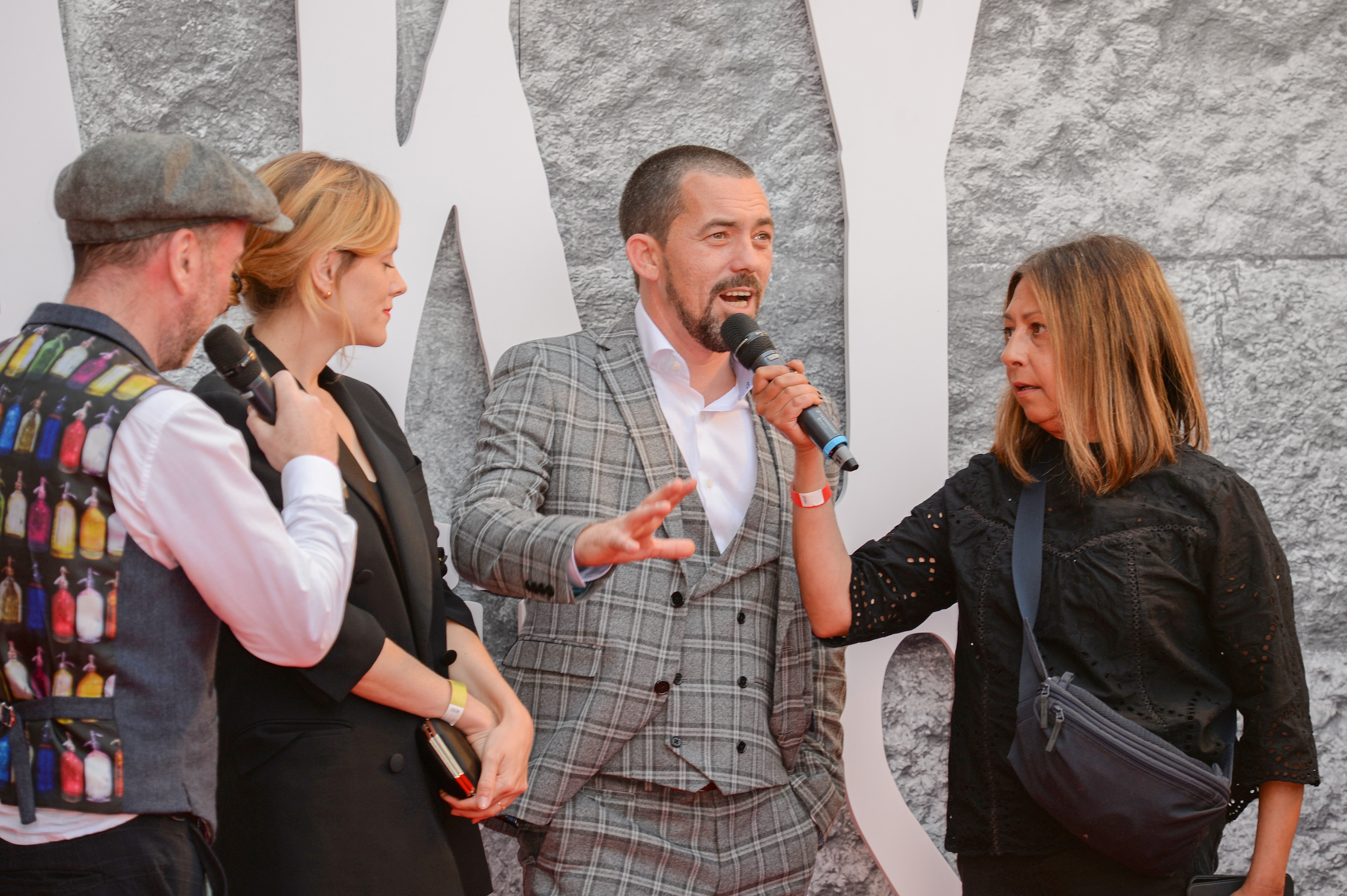 A woman interviews Packy Lee while Sophie Rundle stands beside him.