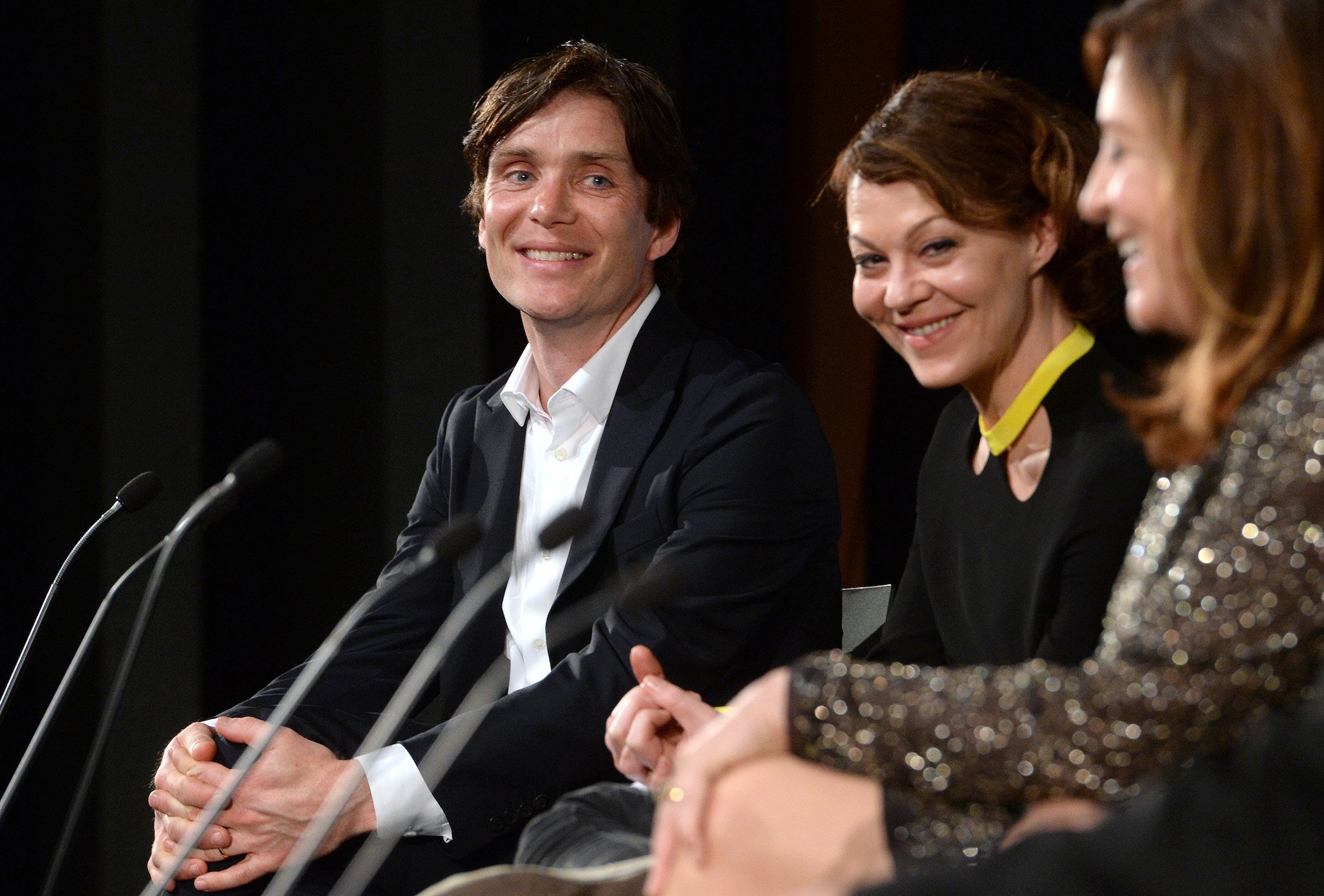 Cillian Murphy from 'Peaky Blinders' Season 6 and Helen McCrory smiling and sitting next to each other against a dark background