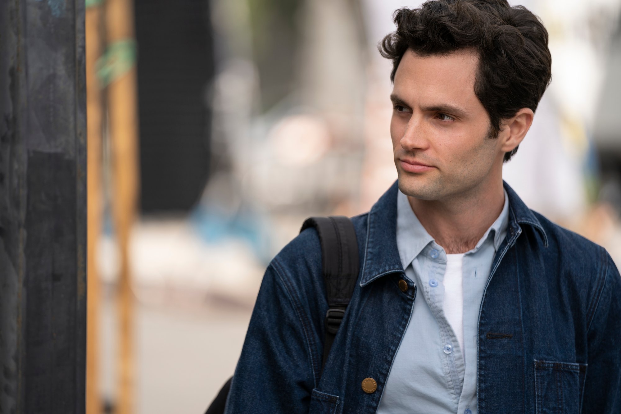 Penn Badgley wears a jean jacket over a blue shirt as Joe Goldberg in 'You'