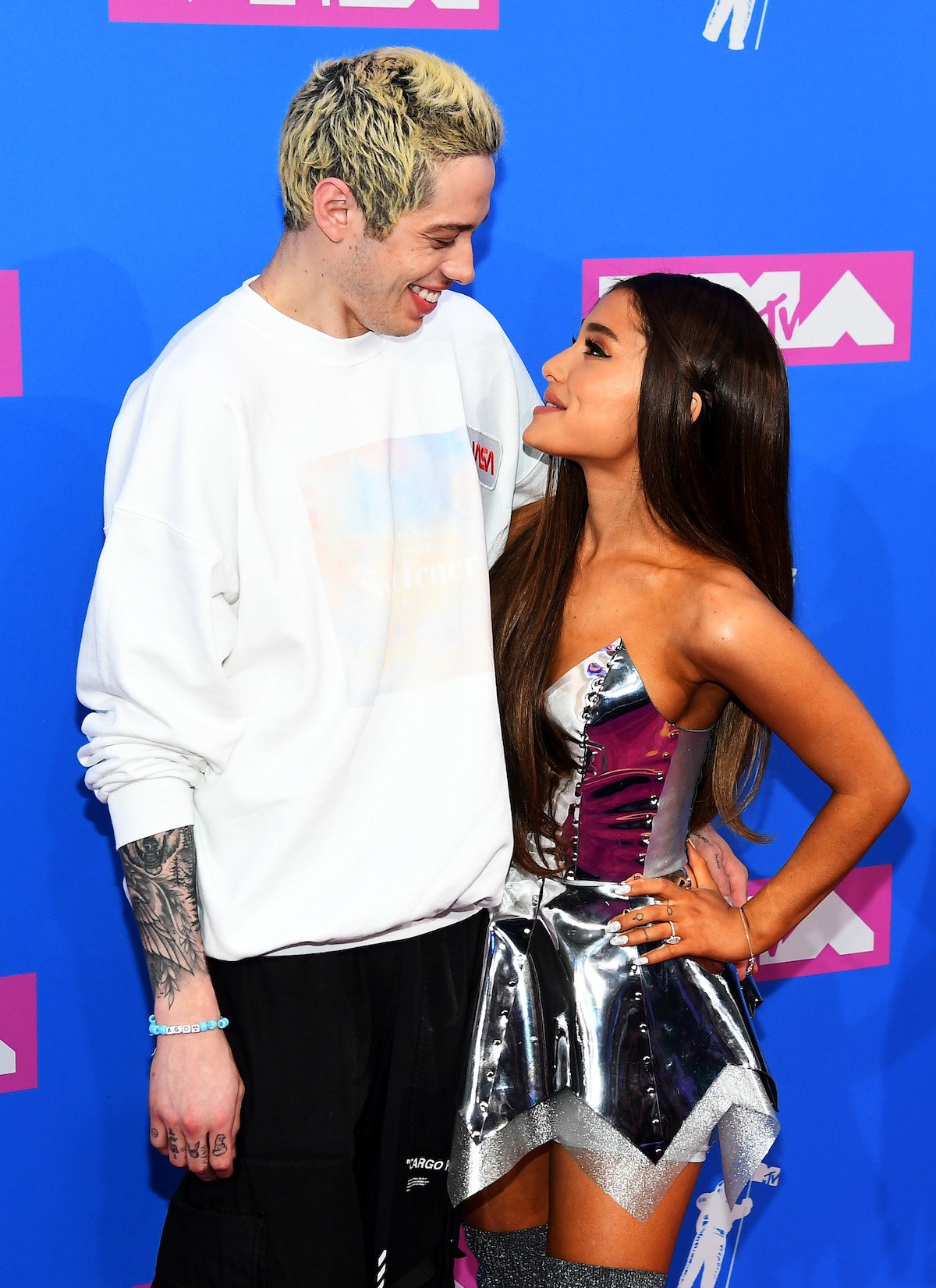 Pete Davidson and Ariana Grande being affectionate on a red carpet.