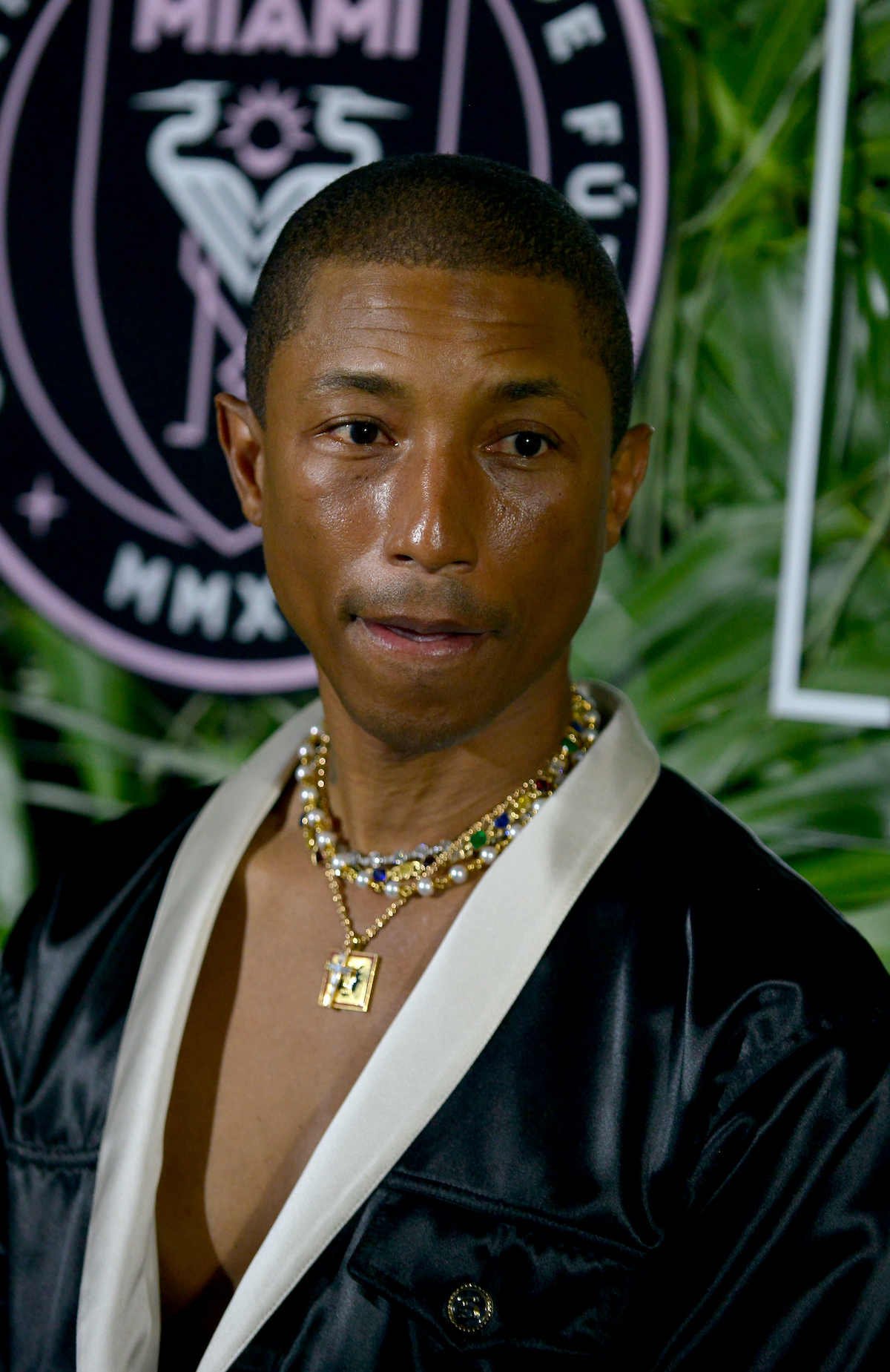 Pharrell Williams wearing a thick chain necklace facing the camera.