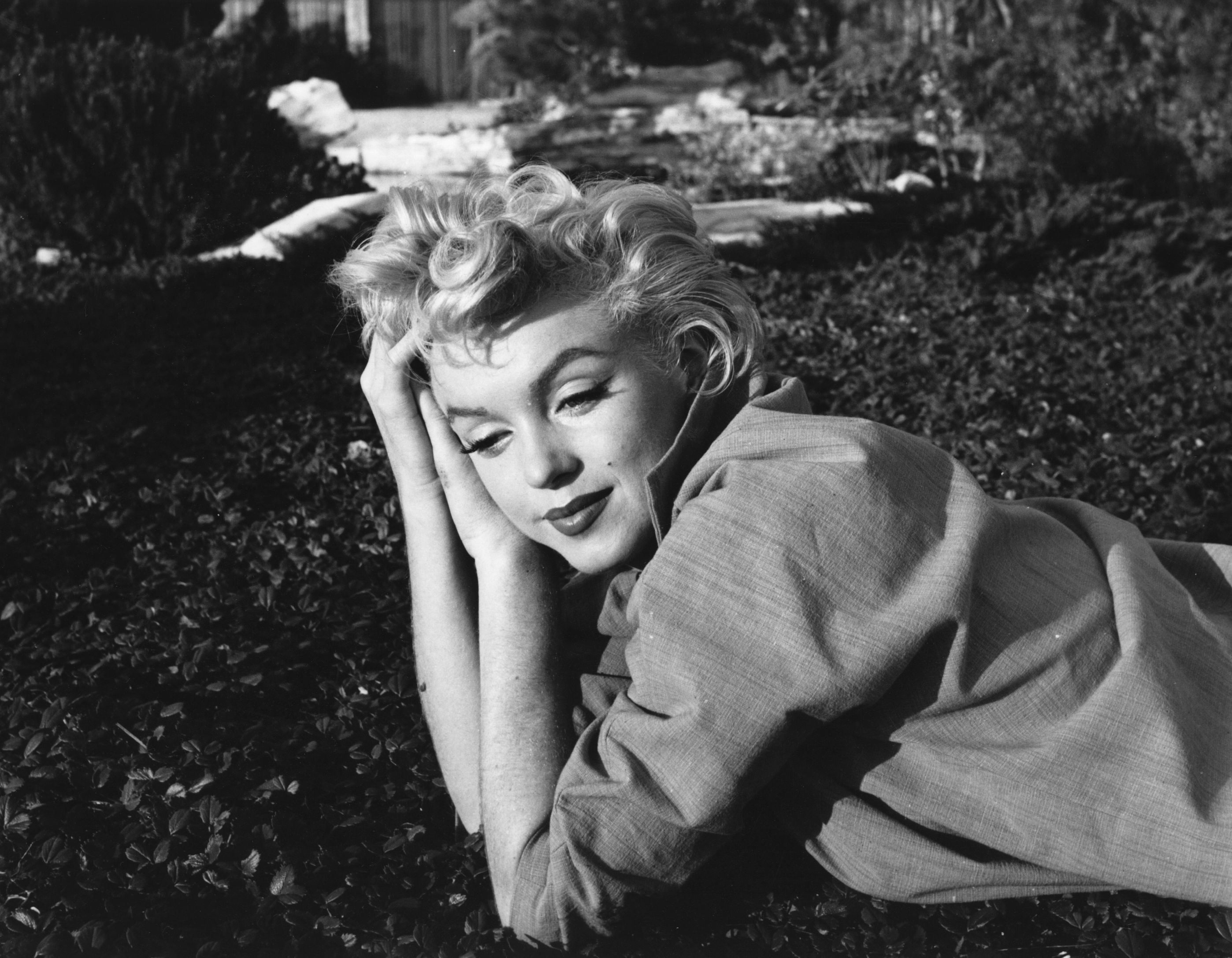 Marilyn Monroe laying down on the ground for photo shoot
