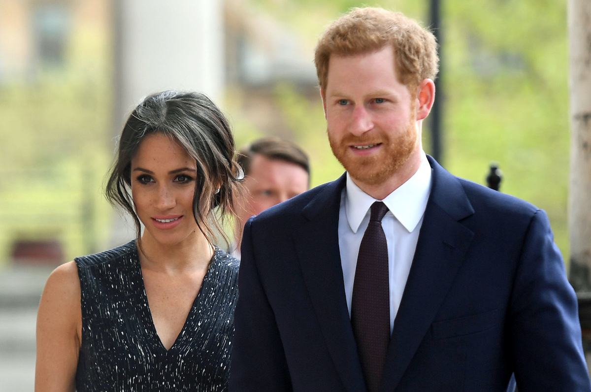 Meghan Markle in dark sleeveless top next to Prince Harry in a suit
