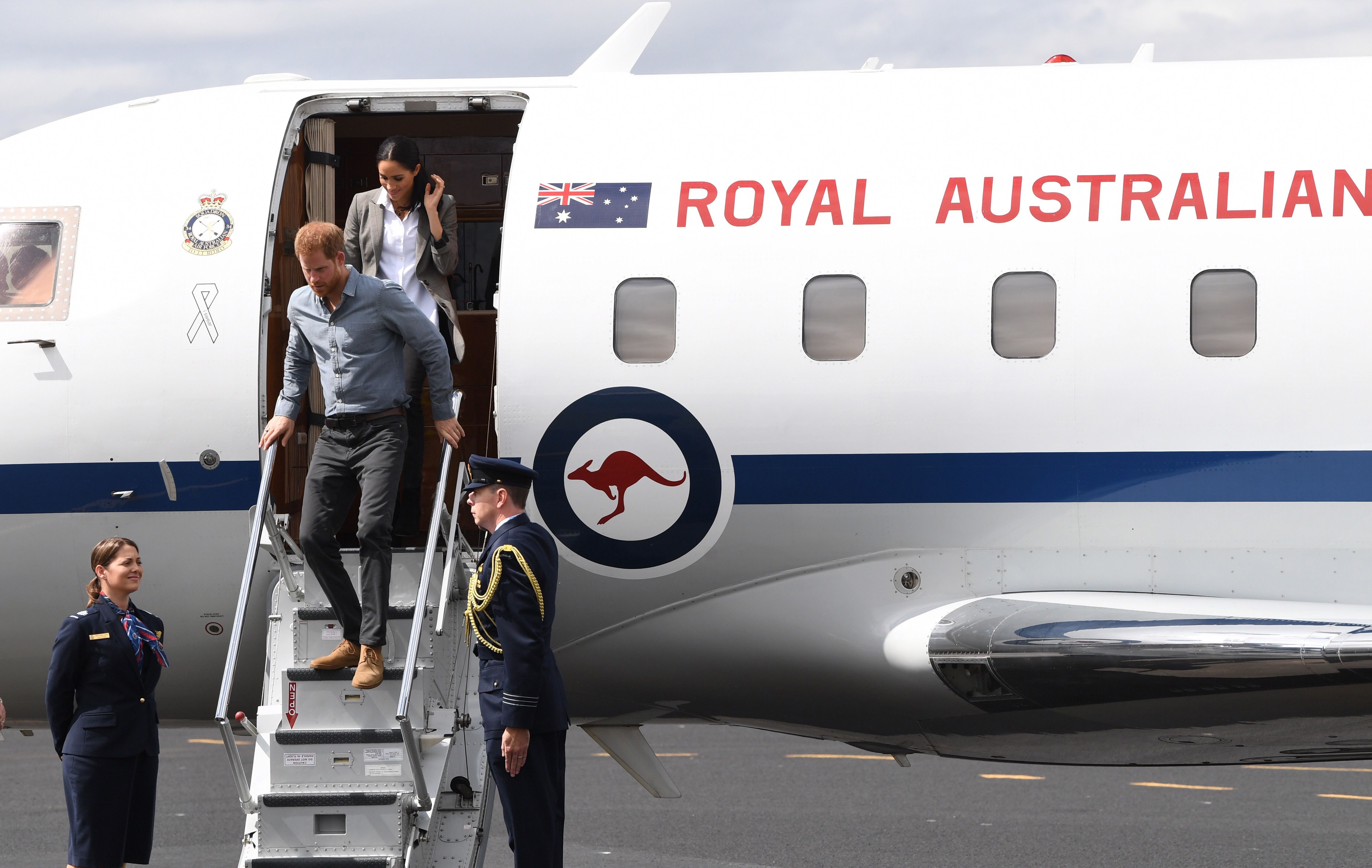 Prince Harry and his wife, Meghan Markle, disembark from their plane in Australia