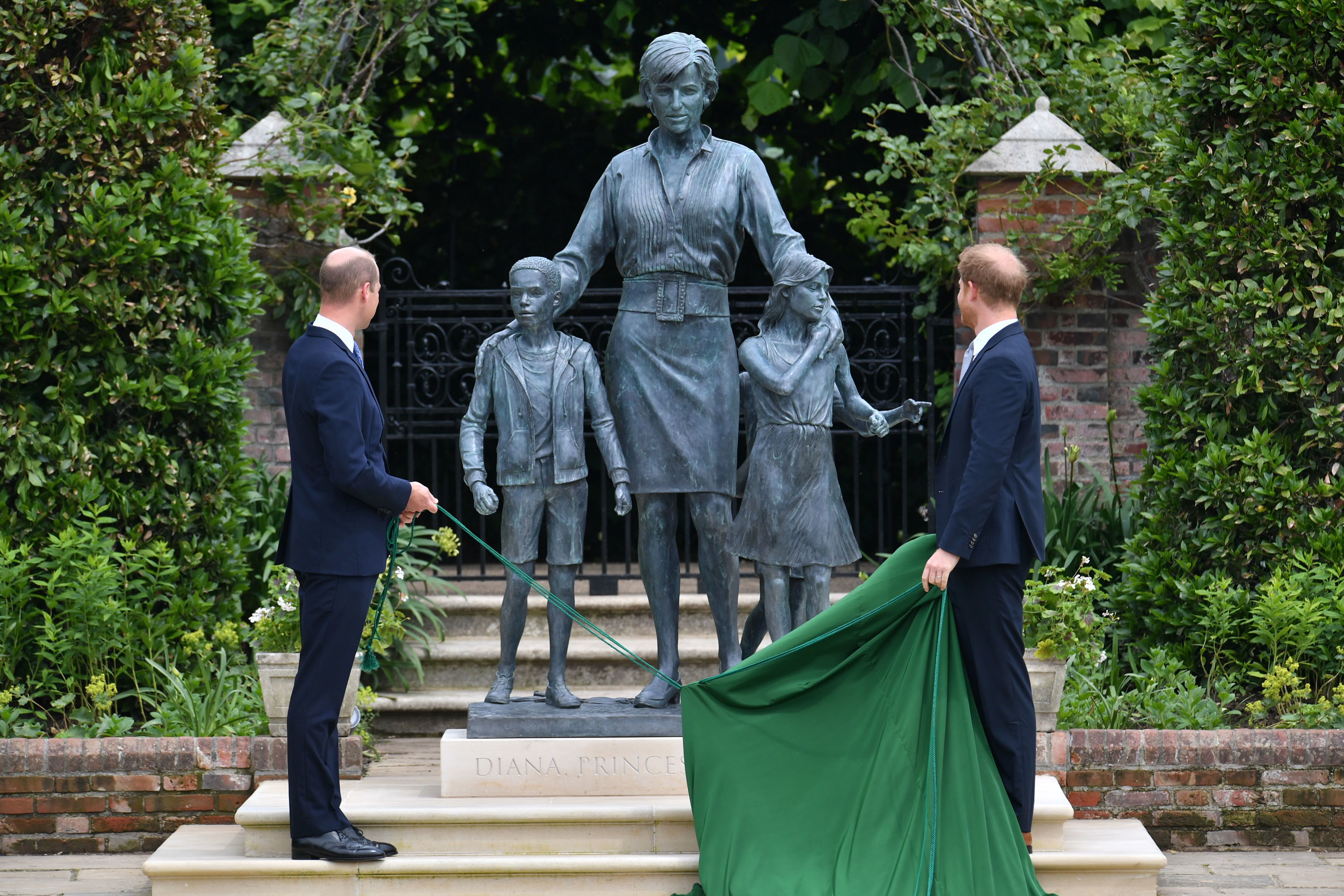 Prince William and Prince Harry wearing dark blue suits as they unveil the statue of their mother Princess Diana at Kensington Palace
