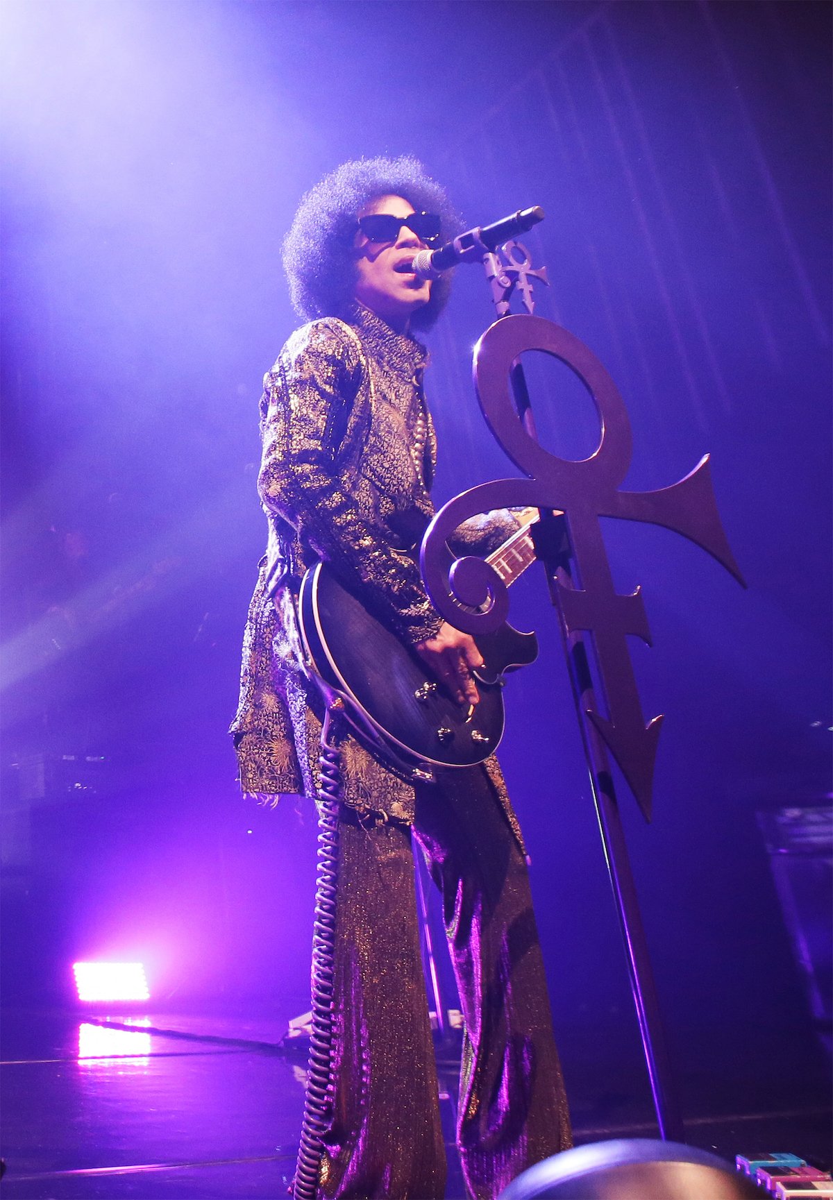Prince performs onstage holding his signature Love Symbol guitar.