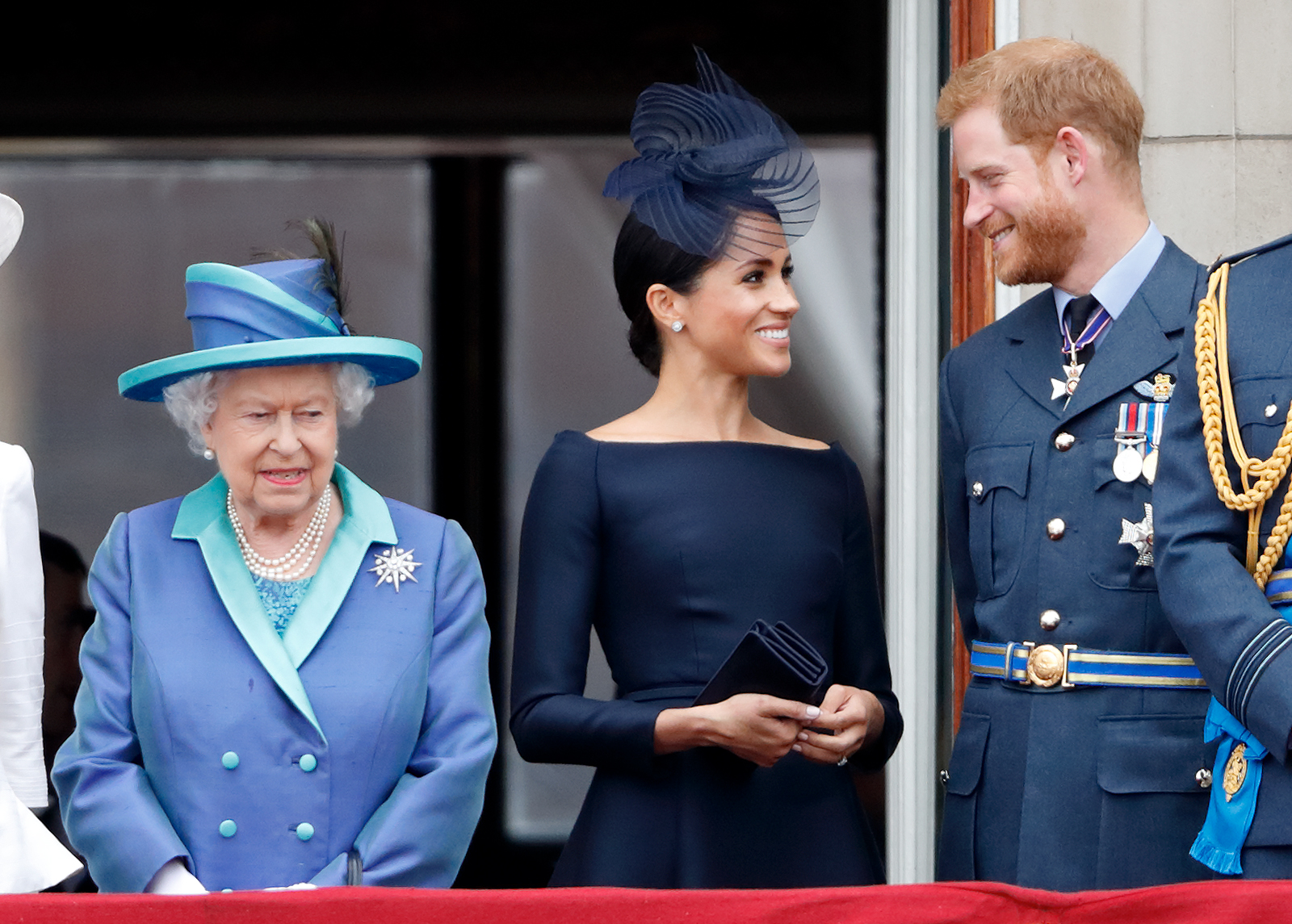 Queen Elizabeth II, Meghan Markle, and Prince Harry standing on the Buckingham Palace balcony
