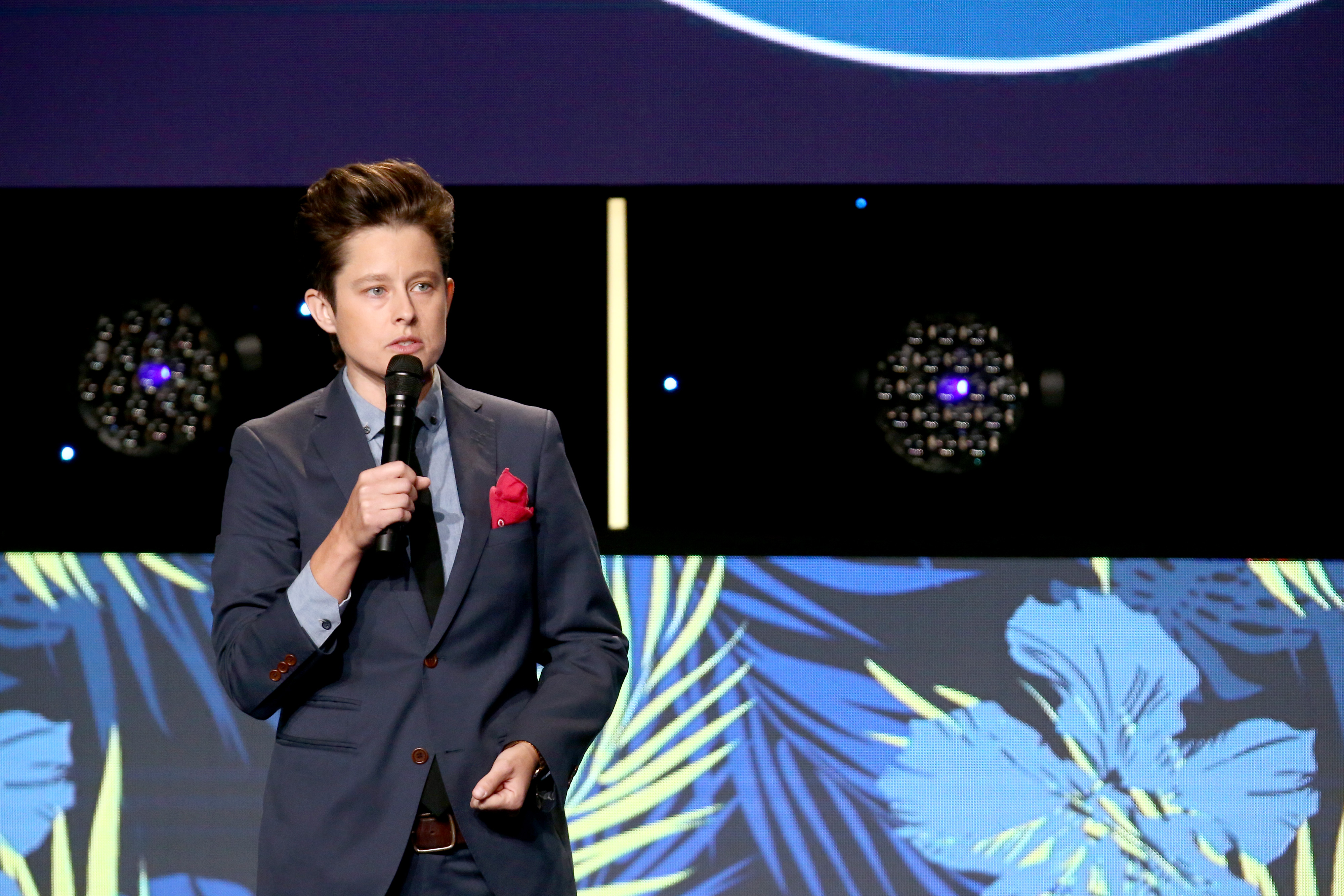 Rhea Butcher stands while holding a microphone