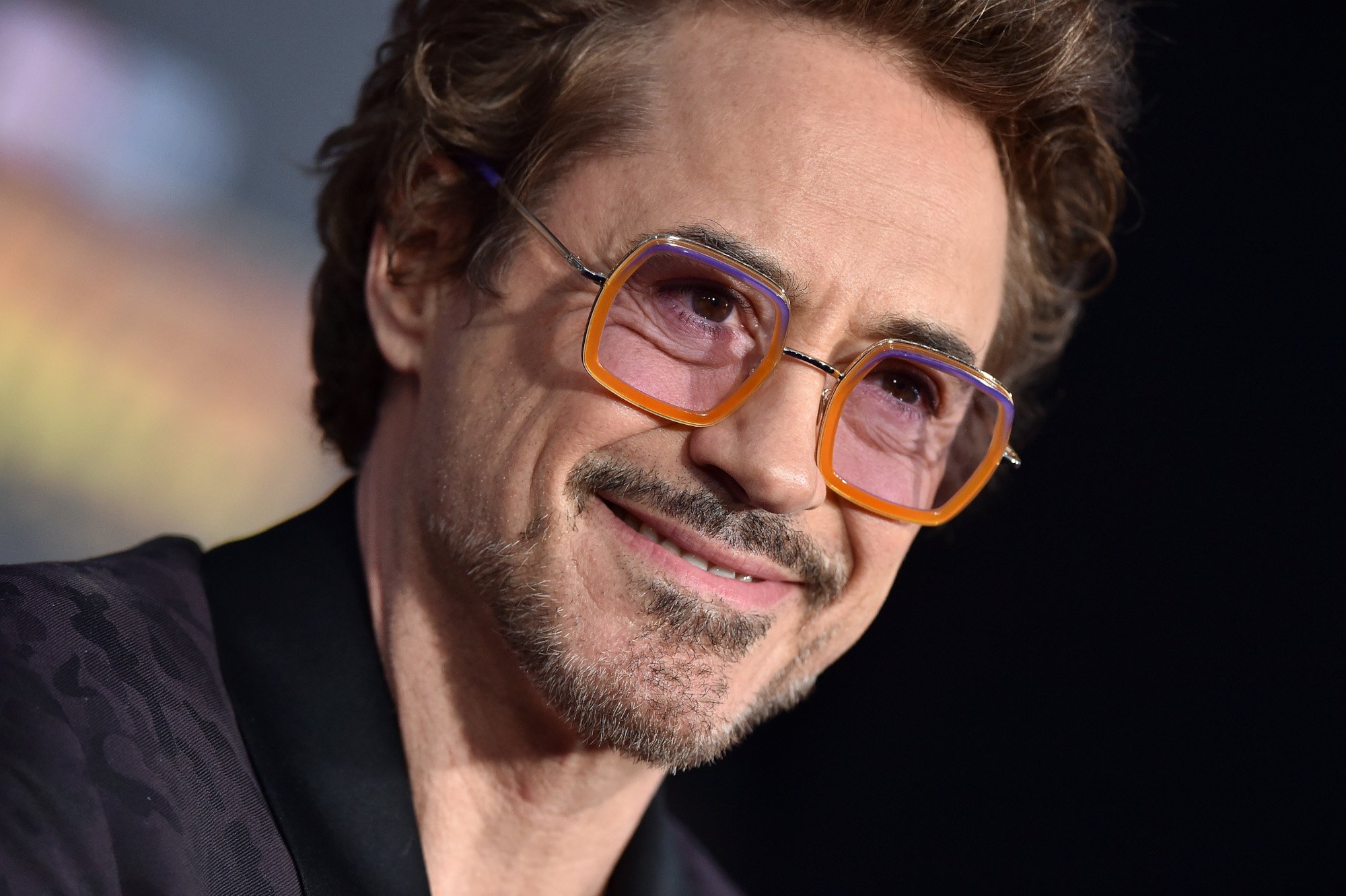 Iron Man star Robert Downey Jr. wearing orange-rimmed glasses with pink tinted lenses and smiling