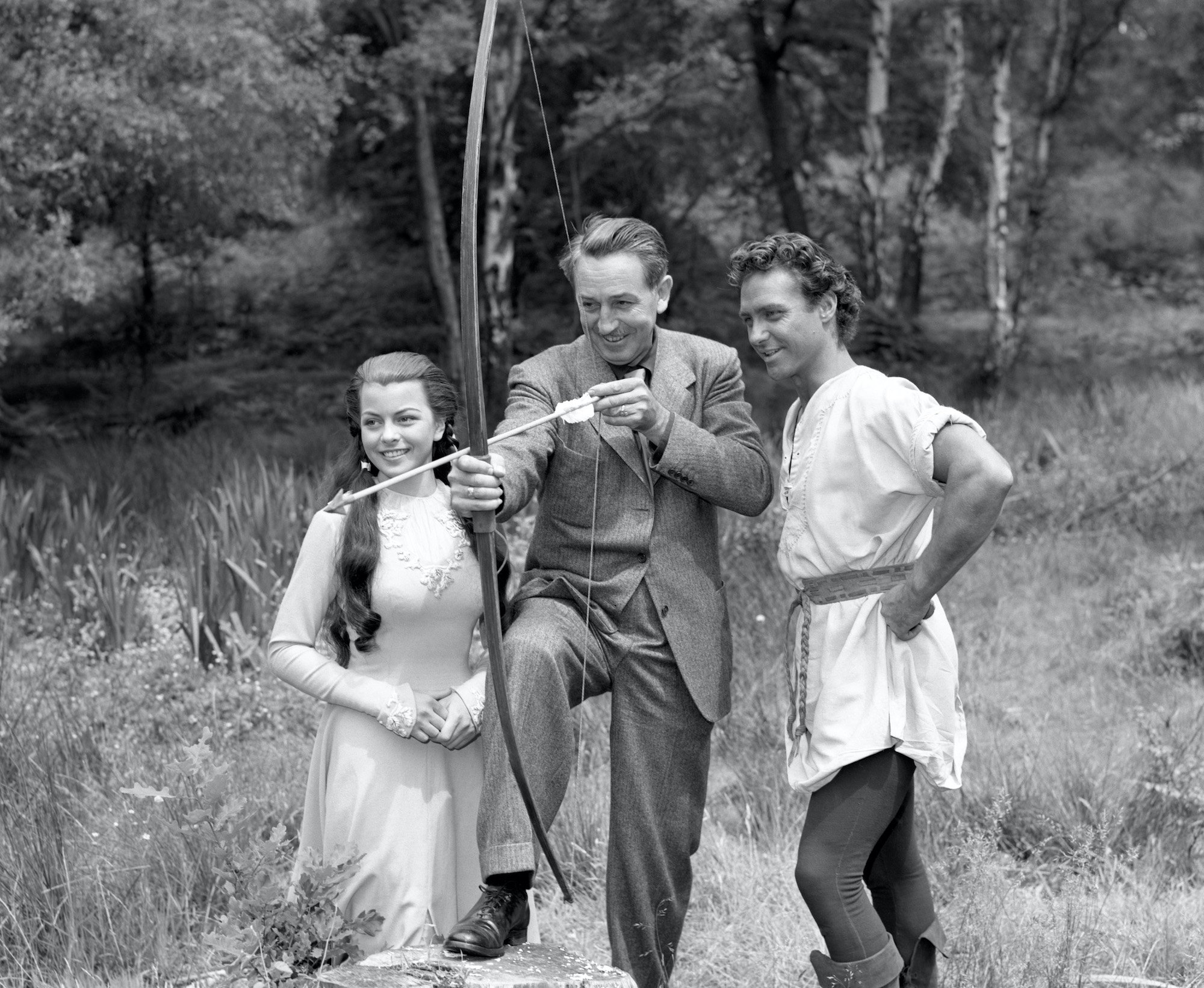 Walt Disney with 'Robin Hood' actor Richard Todd and Joan Rice, in black and white