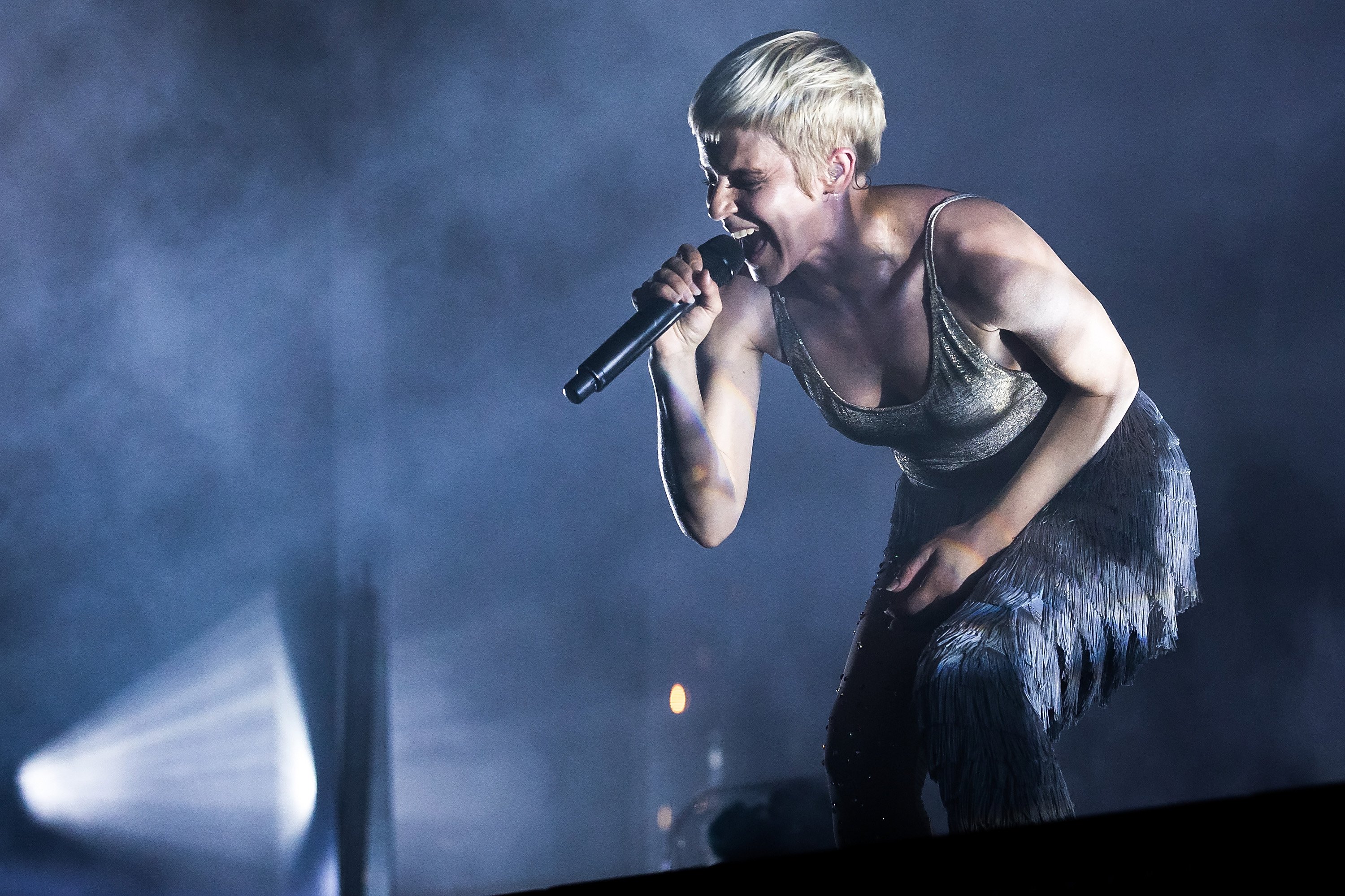 Robyn sings onstage in a gray tank top.