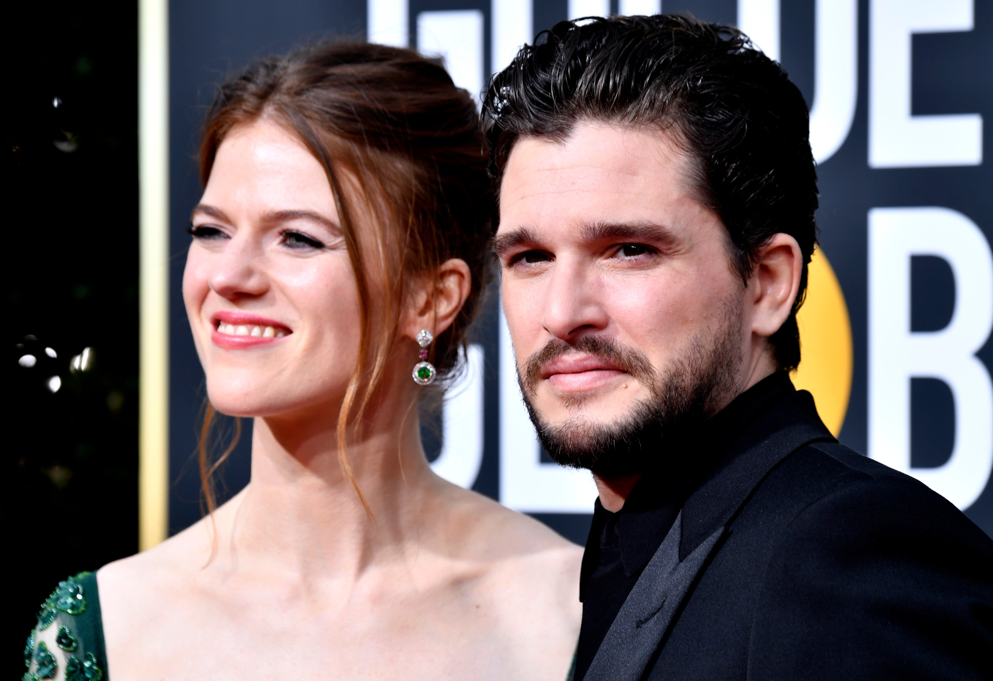 Game of Thrones stars Rose Leslie and Kit Harington. She's on the left with her hair up and a green dress on. He's wearing a suit and standing next to her