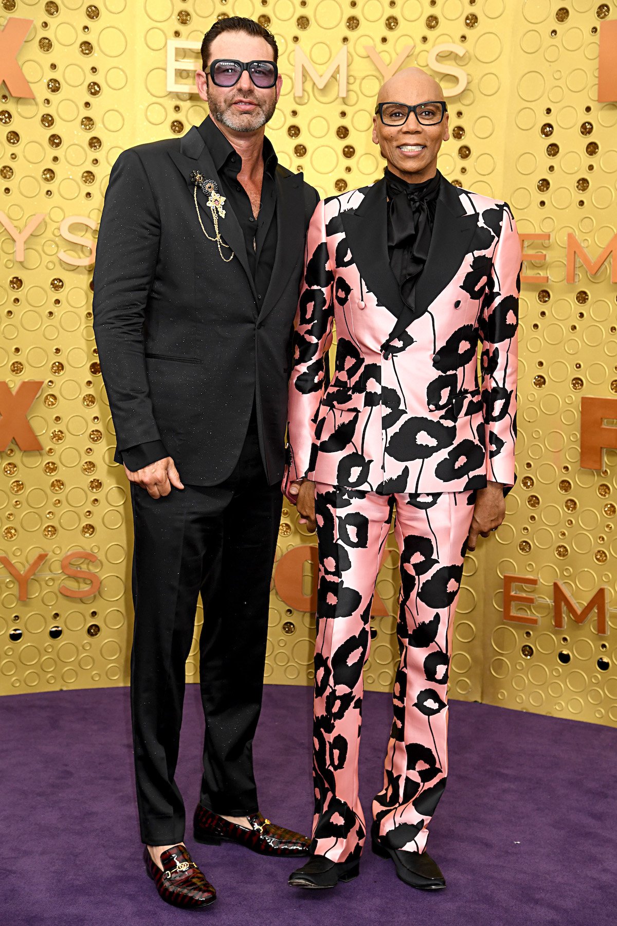 RuPaul and husband Georges LeBar pose together and smile for the camera at an event.